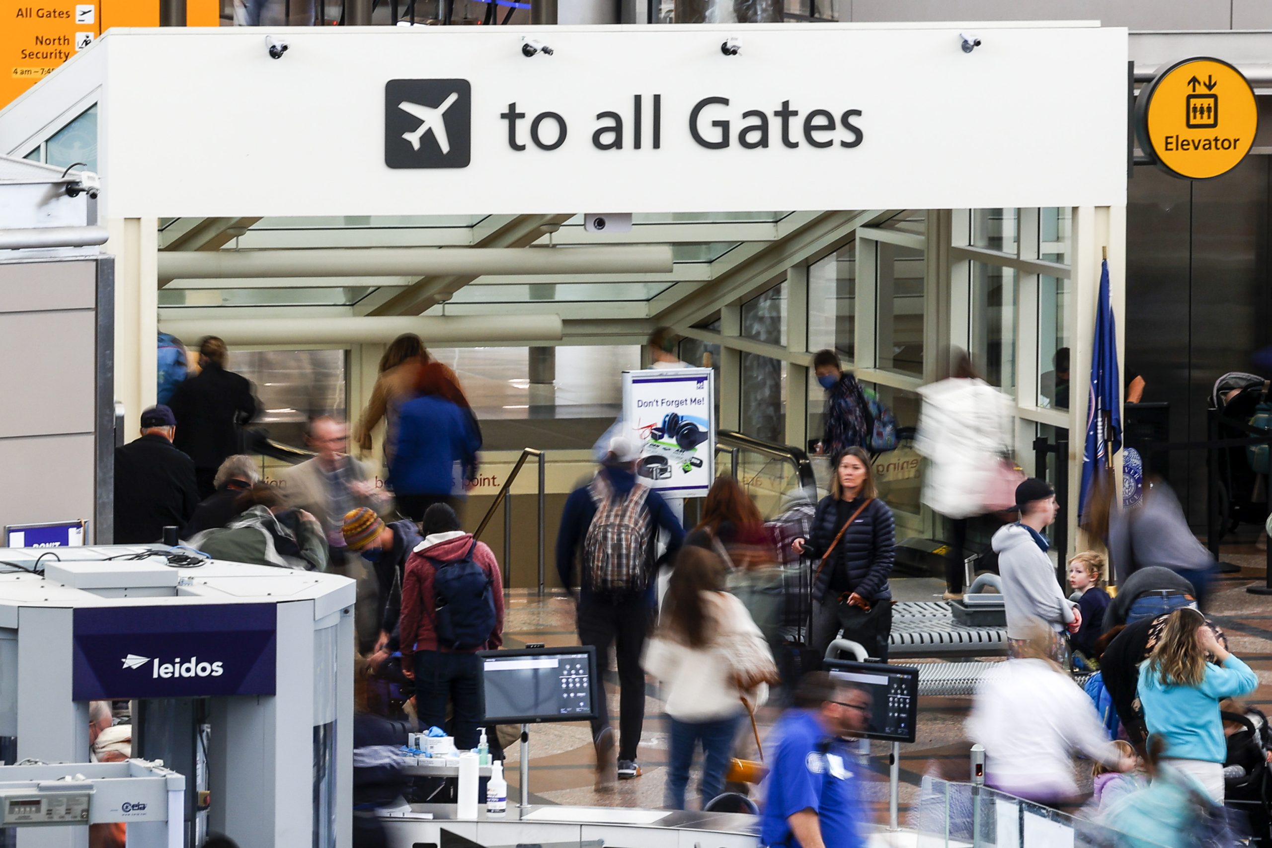 The photo shows people, some blurred in movement, at an airport.