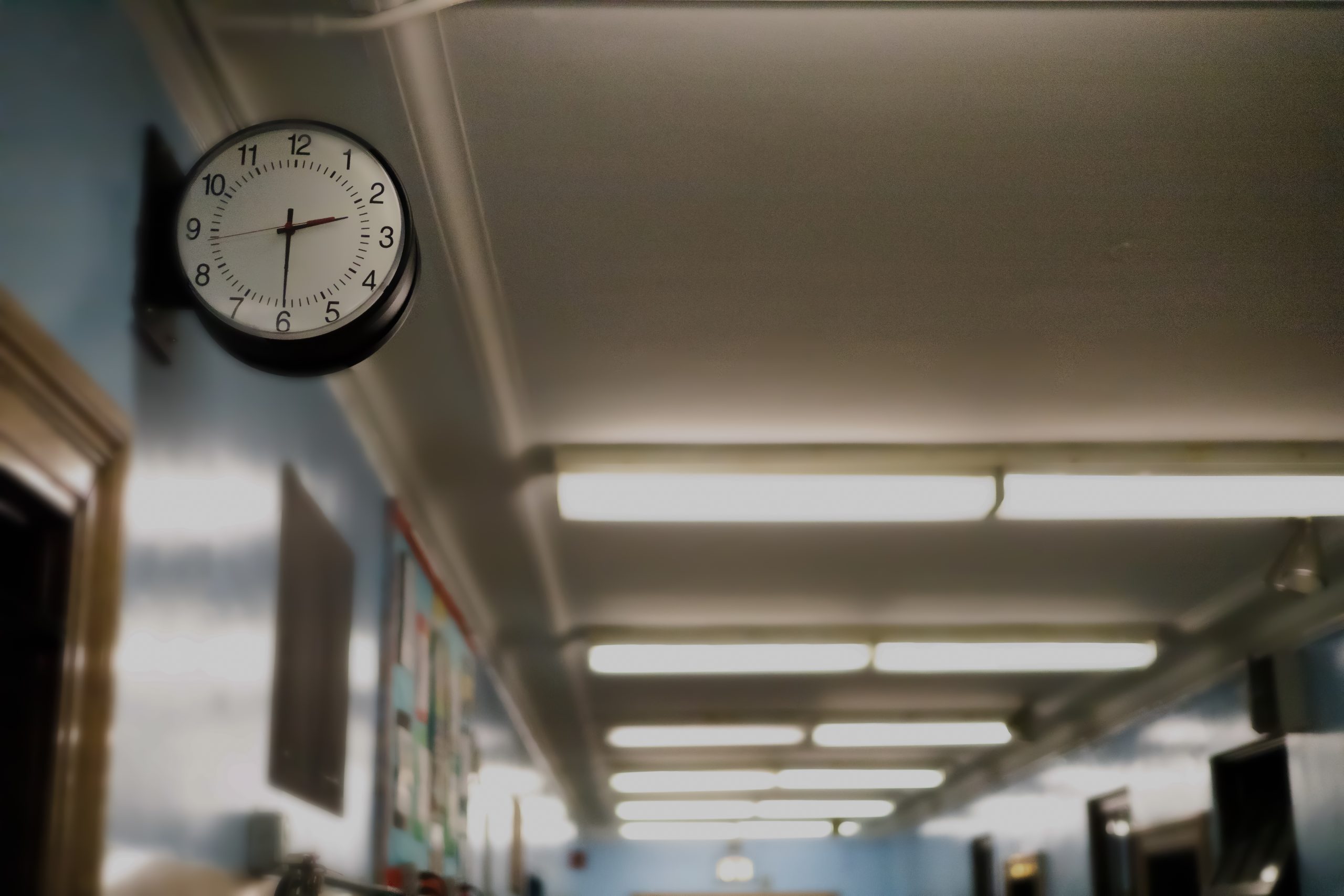 A clock is visible in the foreground of a photo in a school hallway