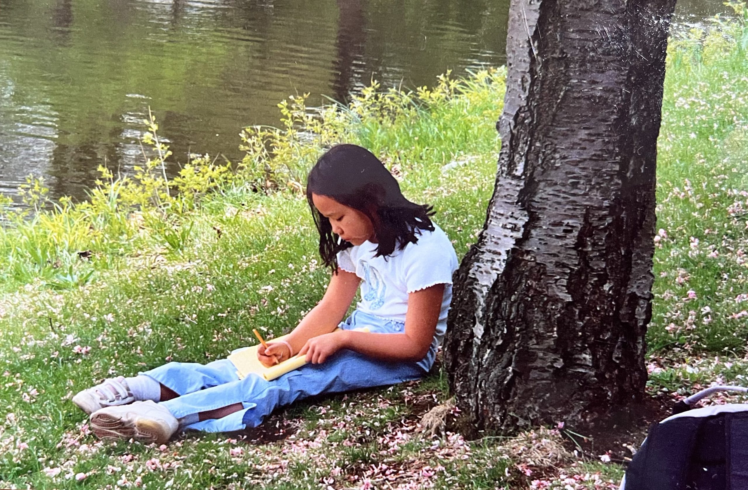 Lian is looking down at the notepad in her lap, holding a pencil