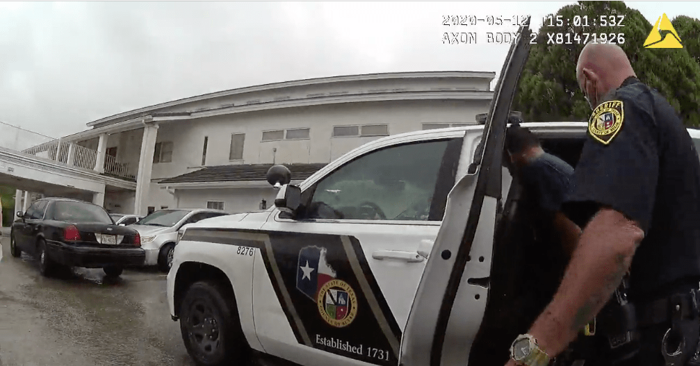 Deputy Patrick Divers helps a teenager into the back seat of a squad car. Neither of their faces are visible.