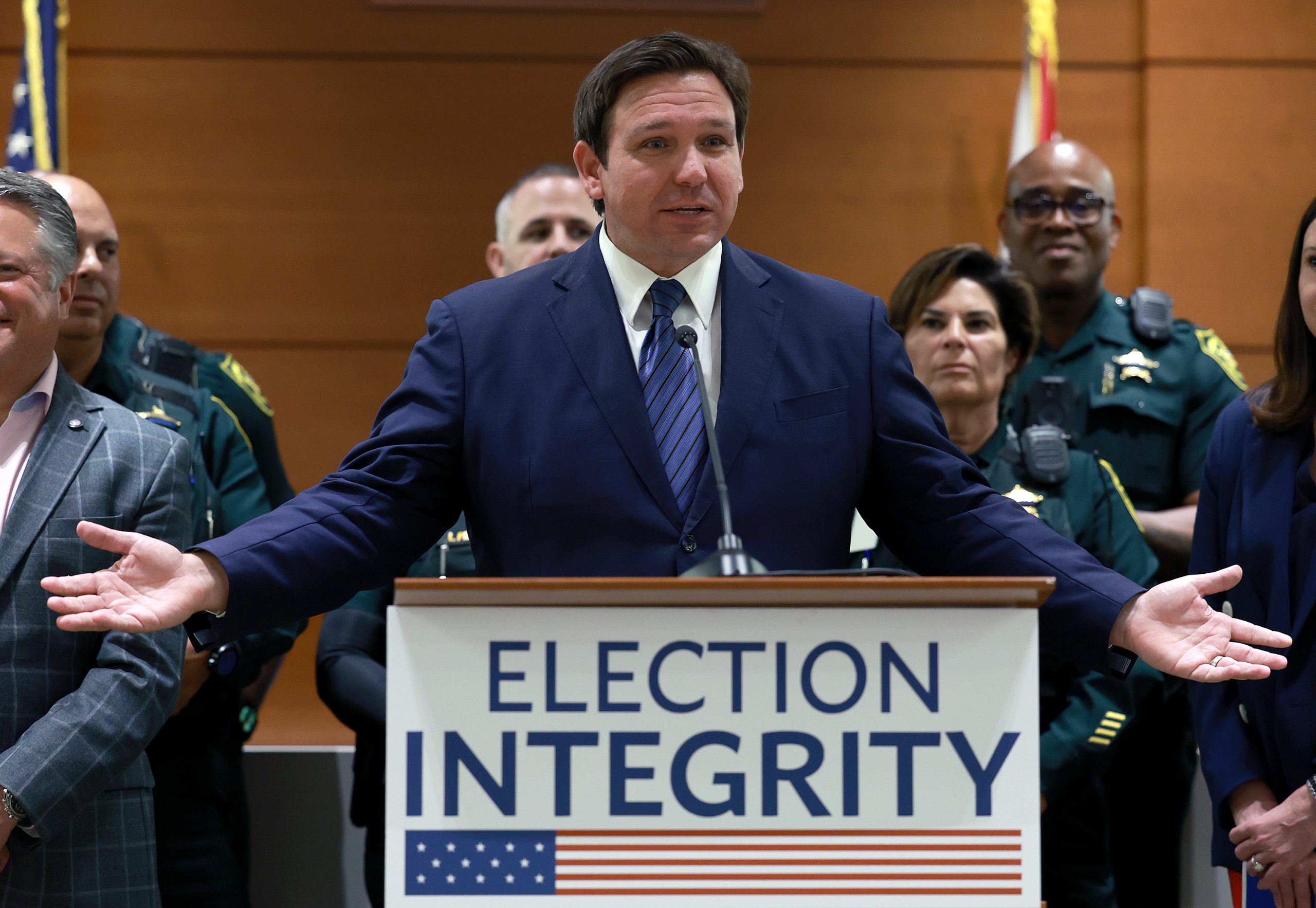 Florida Gov. Ron DeSantis stands behind a lectern with a sign that reads, “Election Integrity.”