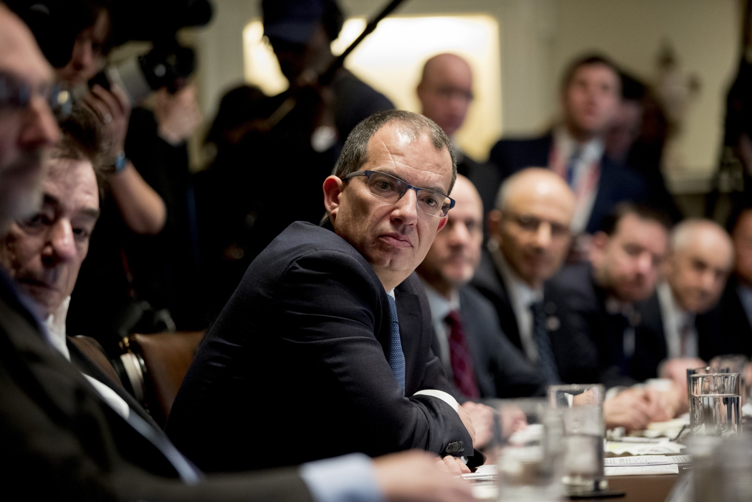 Moderna CEO Stephane Bancel at a conference table, flanked by a row of other White men in suits.