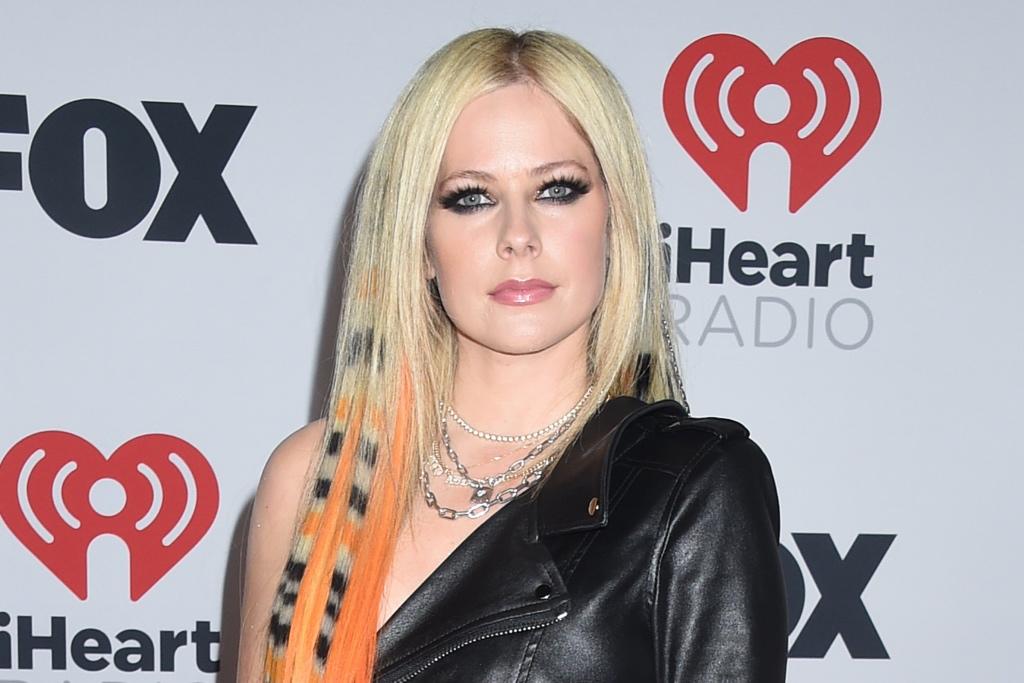 Avril Lavigne rehausse son style punk emblématique dans une minirobe en cuir avec une ceinture à carreaux et des bottes de combat aux iHeartRadio Music Awards