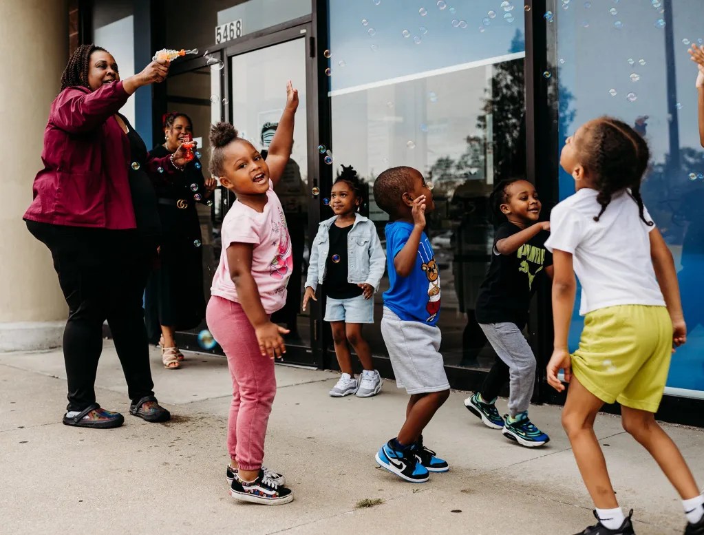 Students at Good Beginnings child care center in Maple Heights take a break from the classroom to play outside the center in the Southgate USA strip mall. Erica Parker, the office administrator, joins them.