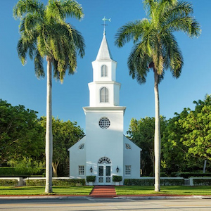 A white church with palm trees representing church insurance.