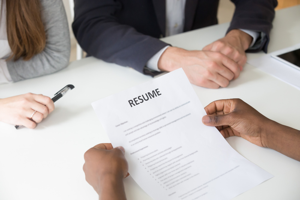 an interviewee submitting their resume to interviewers