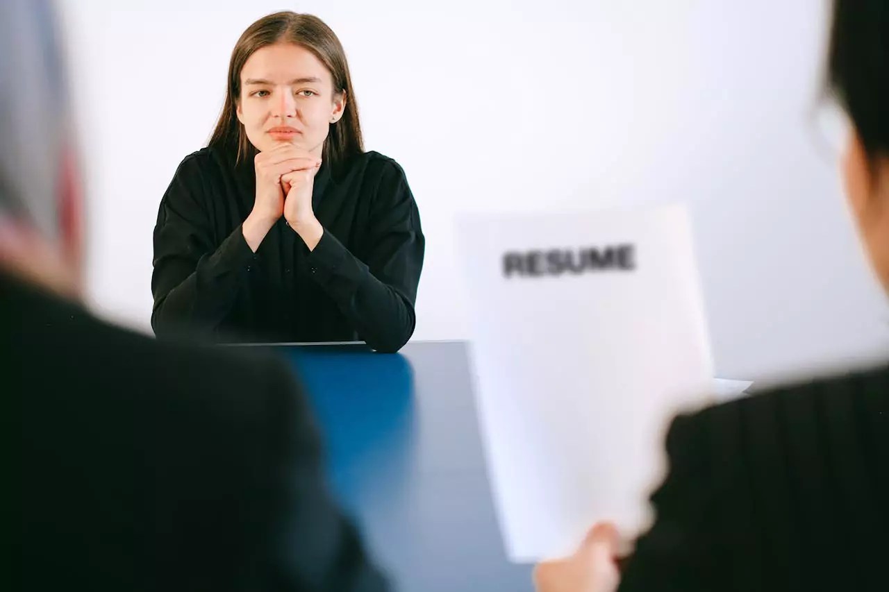 a stressed interviewee in front of interviewers checking her resume