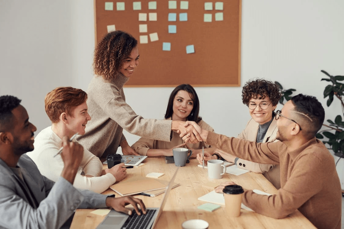 A man and woman demonstrate how to network effectively with a professional handshake among their team.