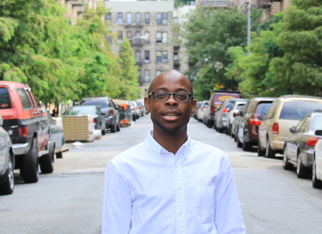 Dr. Jonathan Mathias Lassiter on a New York City street with cars parked on either side and buildings in the background.