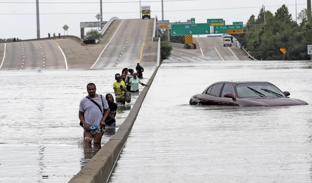 Evacuees wade down a flooded section of Interstate 610 as floodwaters from Tropical Storm Harvey rise, Aug. 27, 2017, in Houston. As the city slowly struggles to recover after Hurricane Beryl left millions without power on Monday, July 8, 2024, experts say it's time to rethink how cities are preparing for and responding to weather disasters. (AP Photo/David J. Phillip, File)