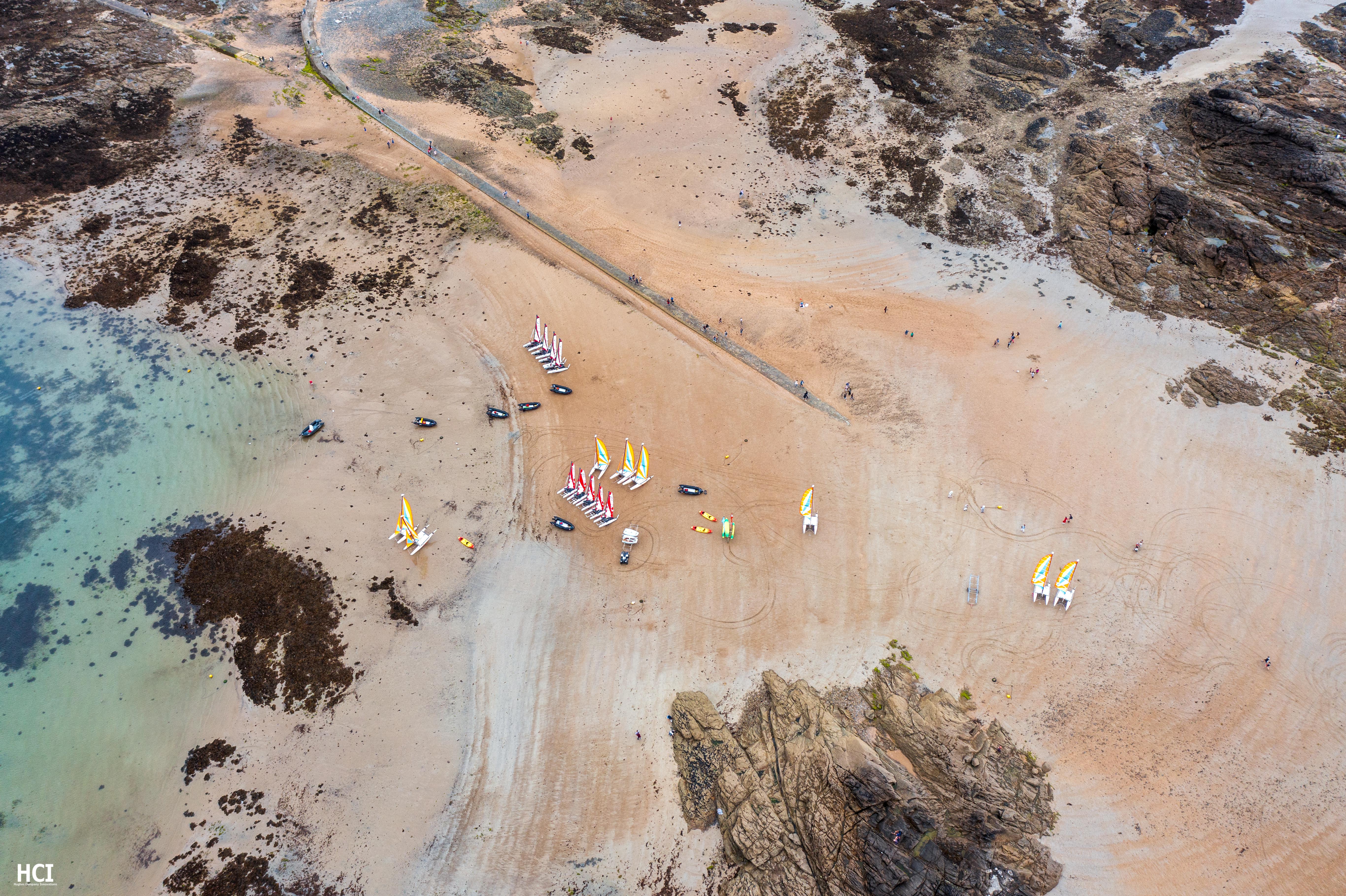 Brilliant aerial view of sail boats on the beach with sailing classes and the incoming tide.  