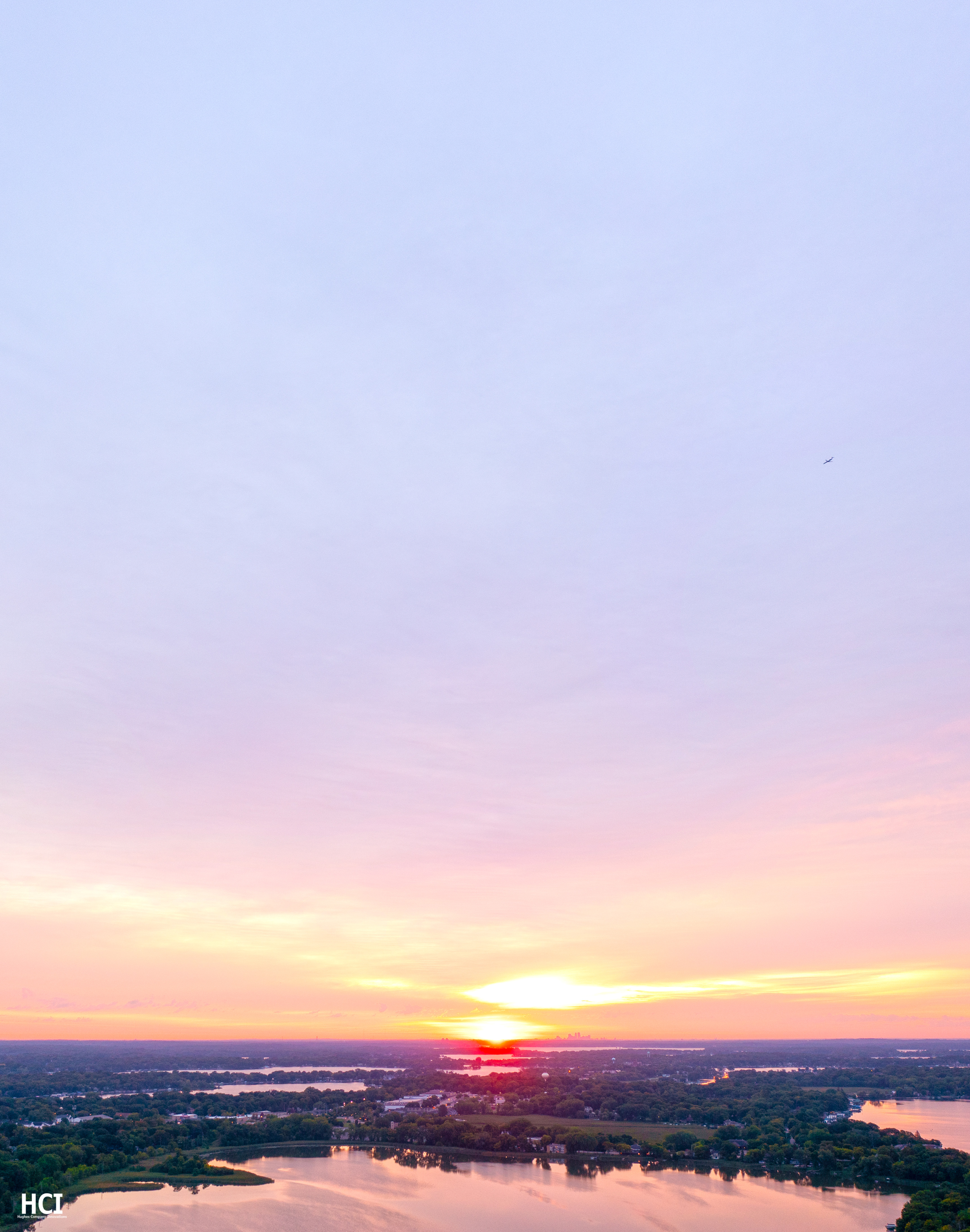 Brilliant aerial sunrise with Minneapolis, Lake Minnetonka, and a flying airplane.
