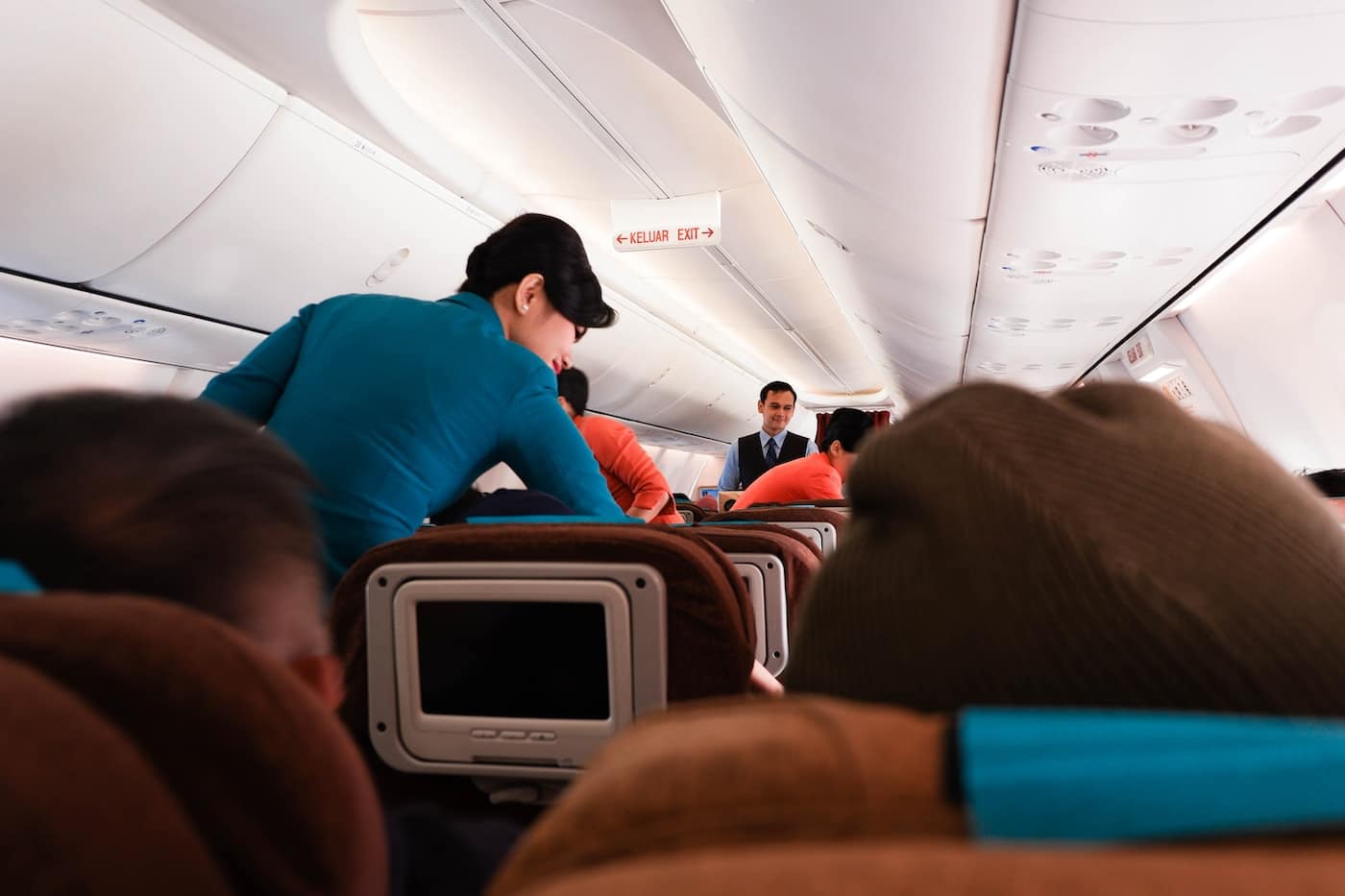 a group of people sitting on seats in an airplane-never swap seats on a plane