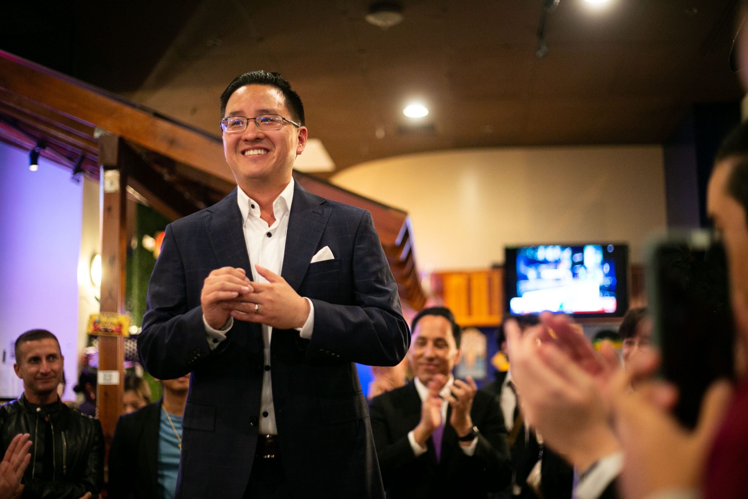 San Diego City Council candidate Kent Lee is applauded at the Crab Hut in San Diego on Nov. 8, 2022. / Photo for Brittany Cruz-Fejeran for Voice of San Diego