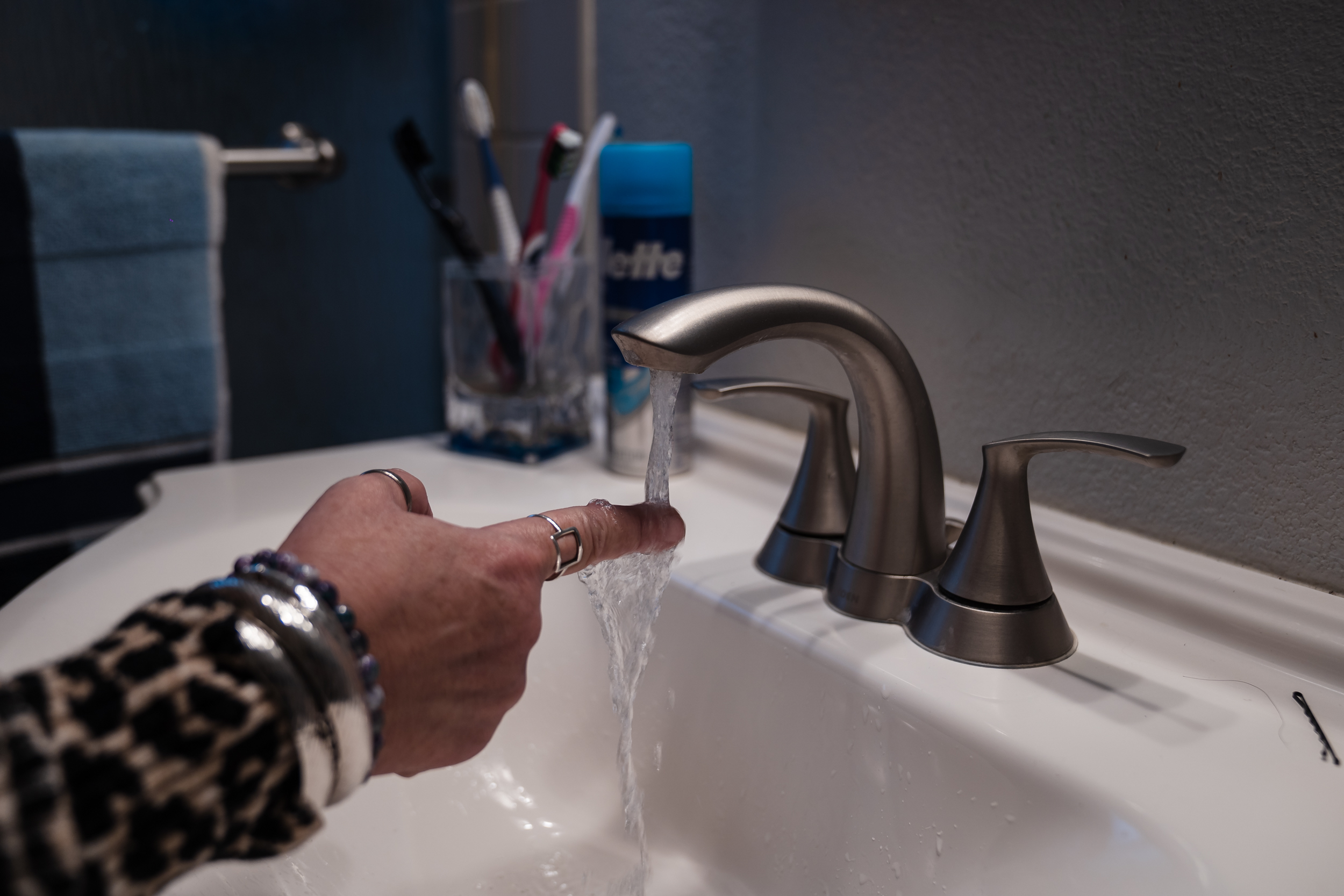 Teresa Morse sticks her hand under the faucet in her bathroom in Golden Hill on March 10, 2023. Morse says it can take several minutes to get warm water.