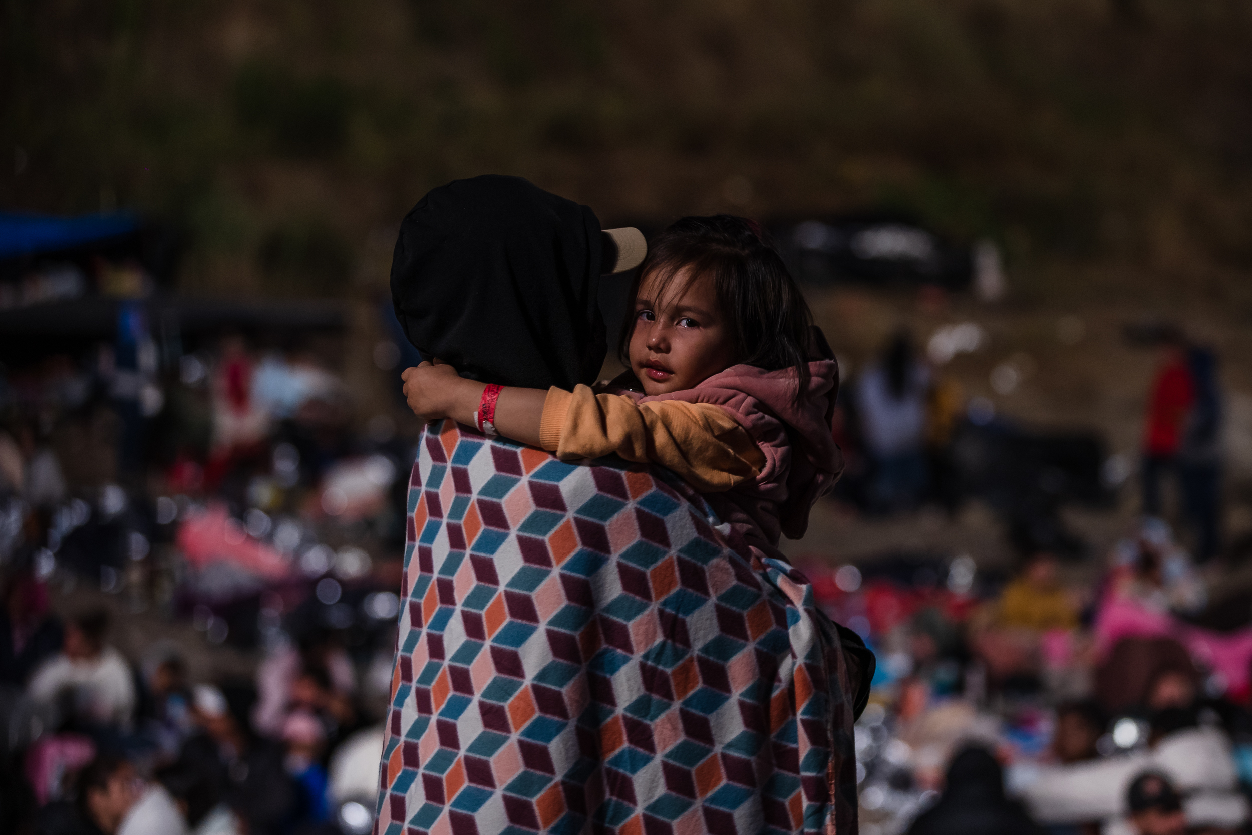 Asylum seekers can be seen through the border wall in San Ysidro on May 11, 2023.