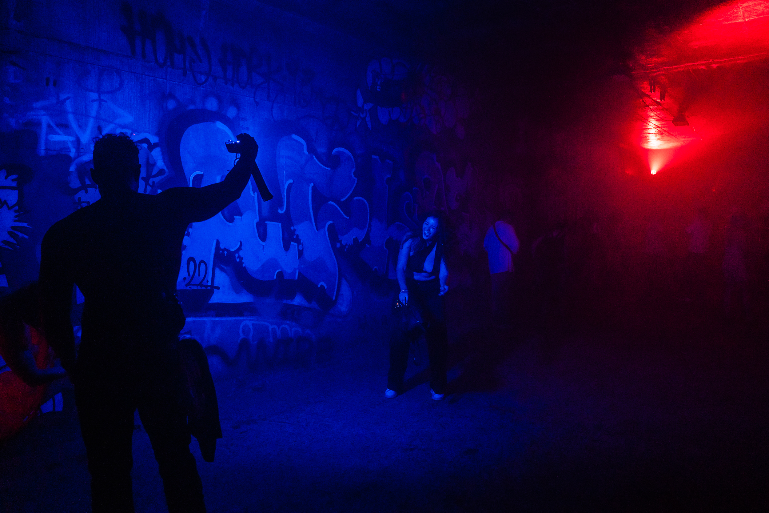 A man lights a woman so a friend can take a photo in an underground tunnel.