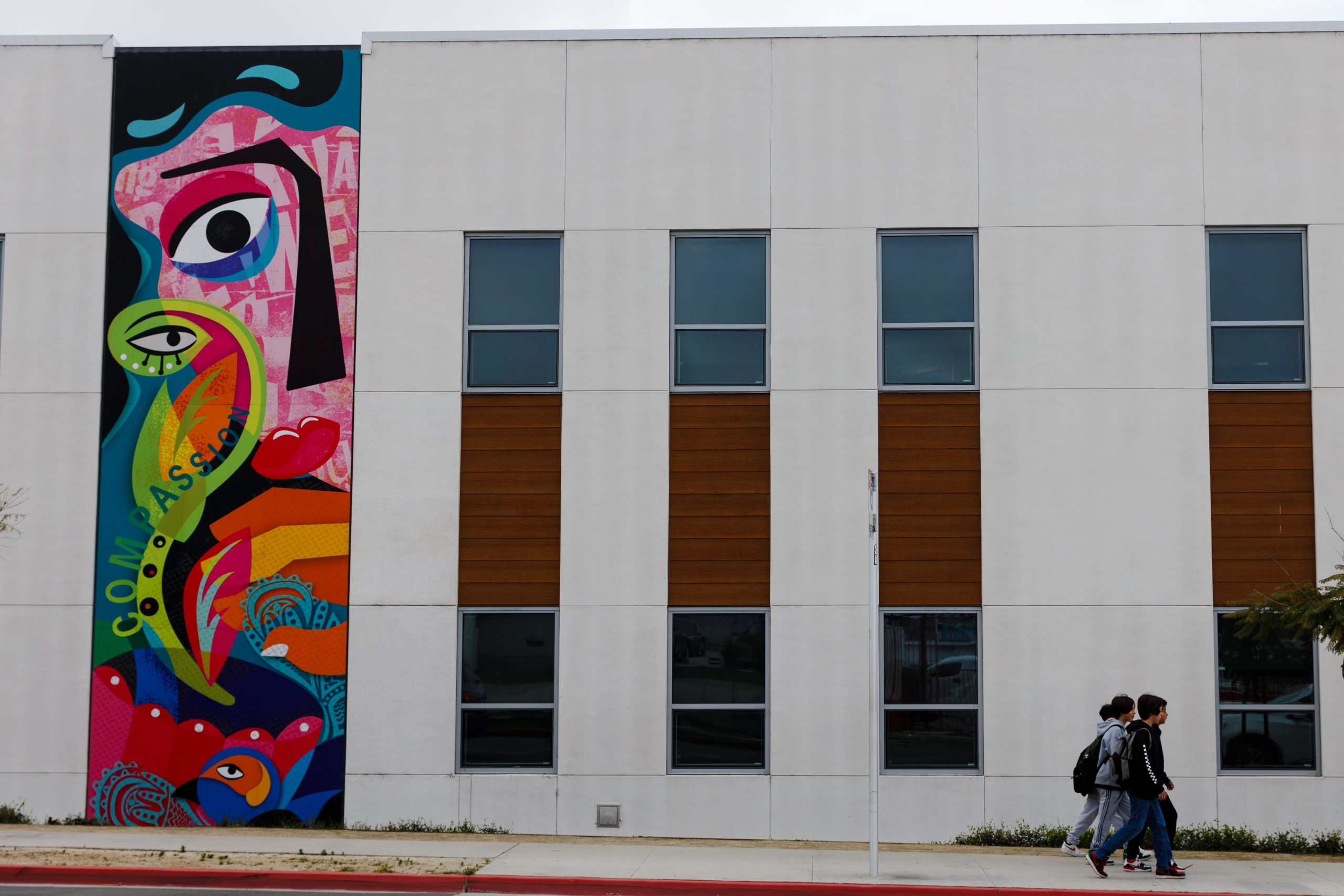 Students walk past a mural at the Logan Memorial Educational Campus in the Logan Heights neighborhood on March 26, 2024./ Photo by Kristian Carreon for Voice of San Diego