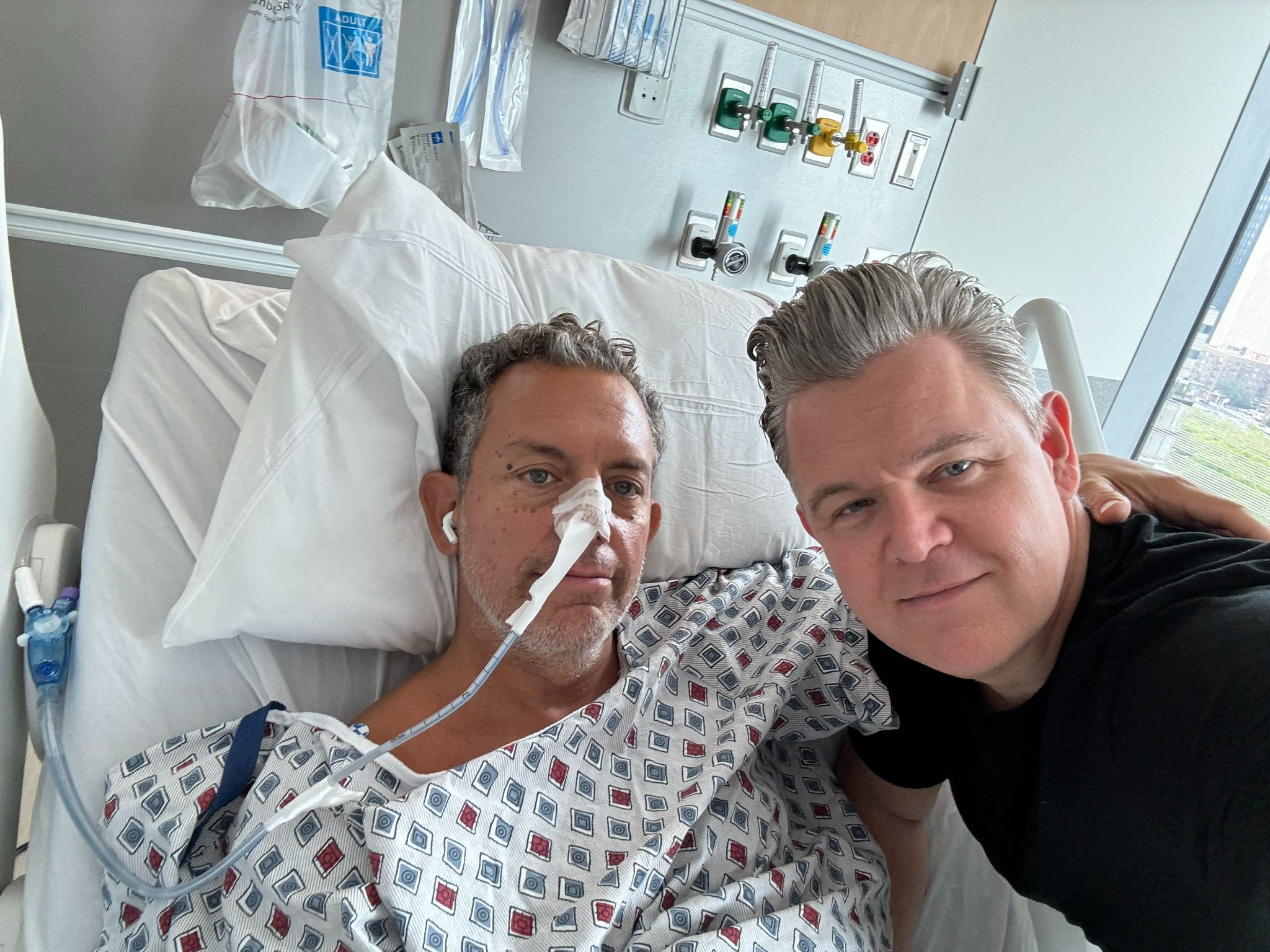 Tony Simone in hospital bed with husband Jason