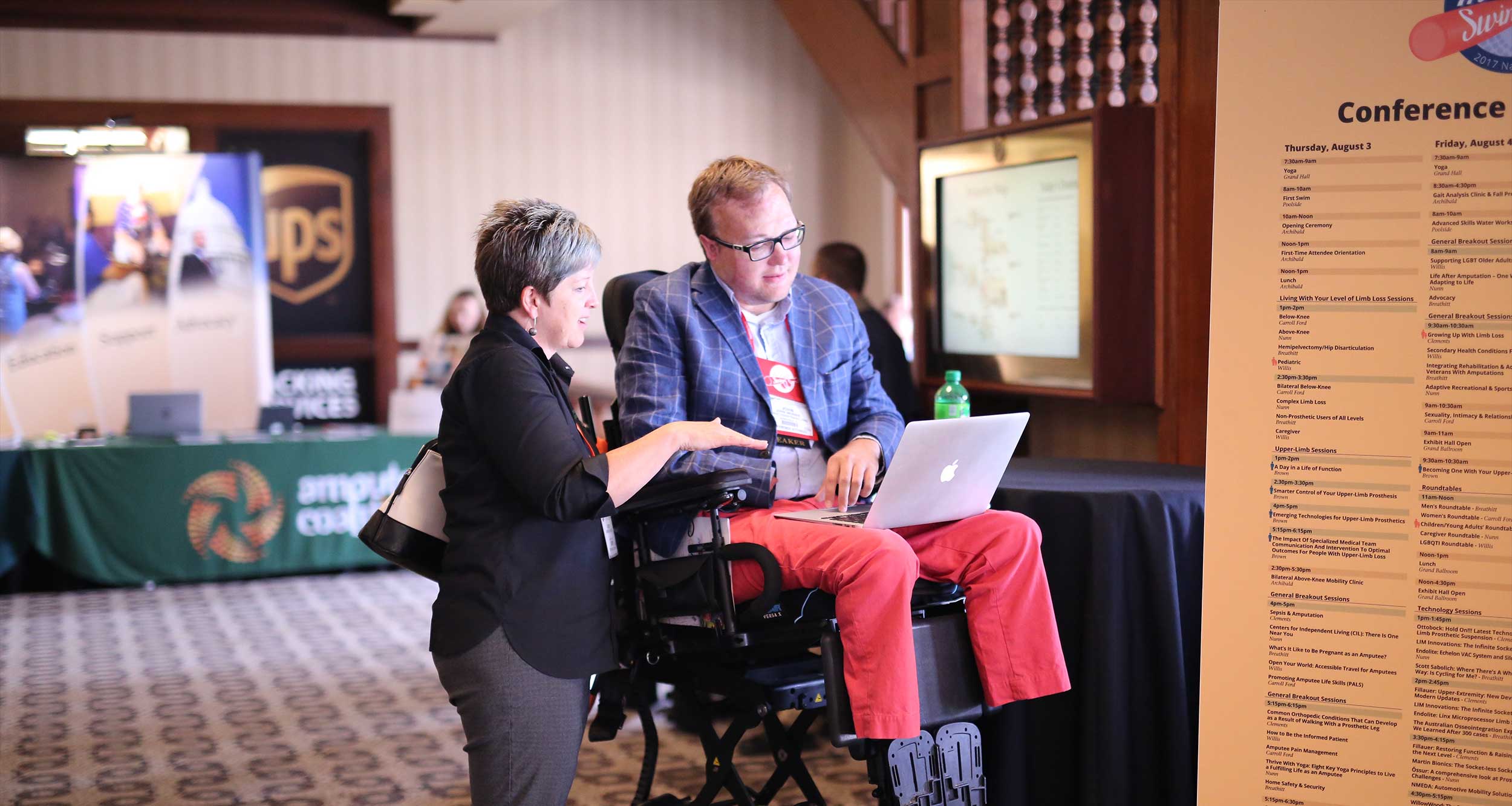 John discussing something with a woman at a conference.