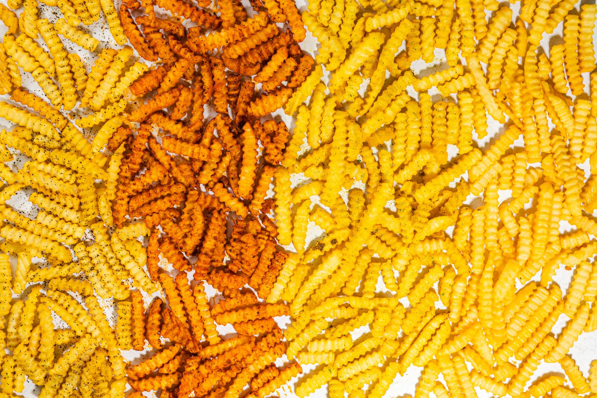 An assortment of golden-brown, crispy fries with a perfectly seasoned coating, arranged in a pile. The fries vary in shape and size, each showcasing a crunchy texture and mouthwatering appeal, ready to be enjoyed with a side of dipping sauces.