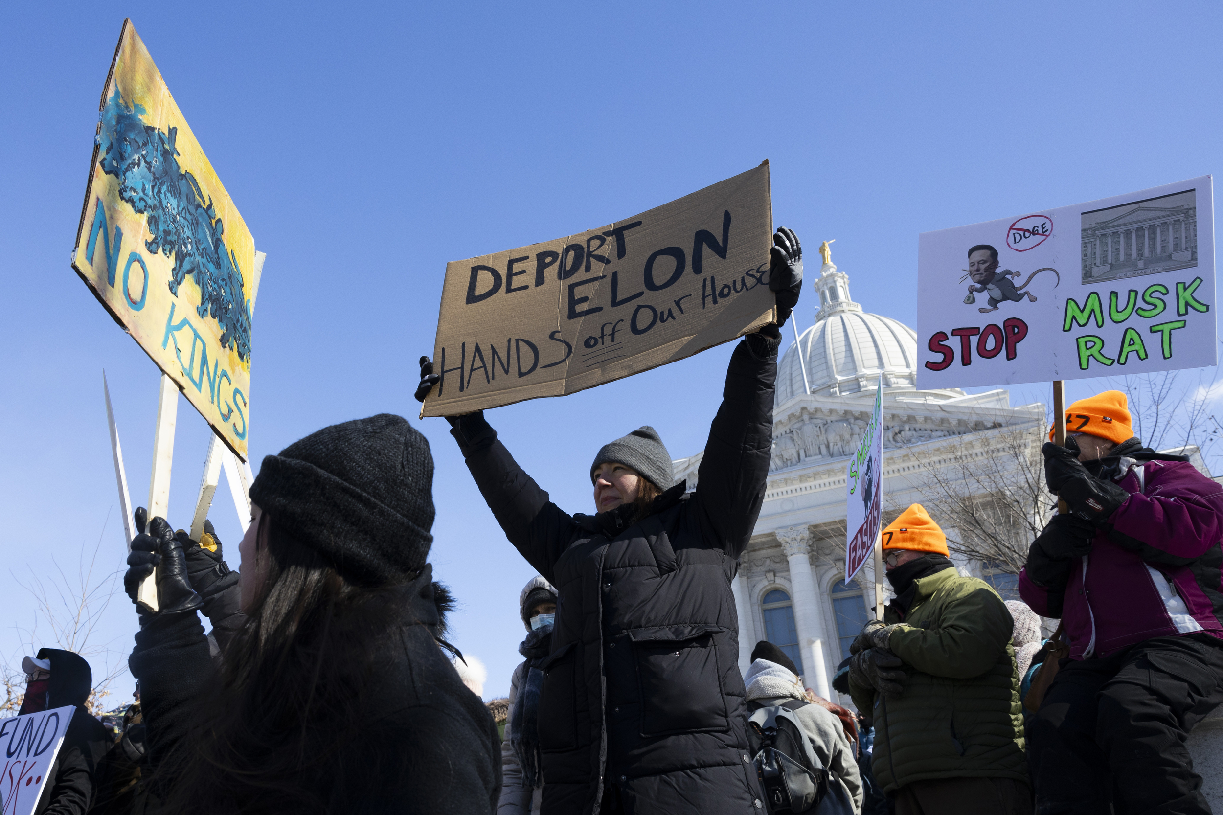 Outside the Wisconsin Capitol, people hold signs saying “NO KINGS,” “DEPORT ELON” and “STOP MUSK RAT”