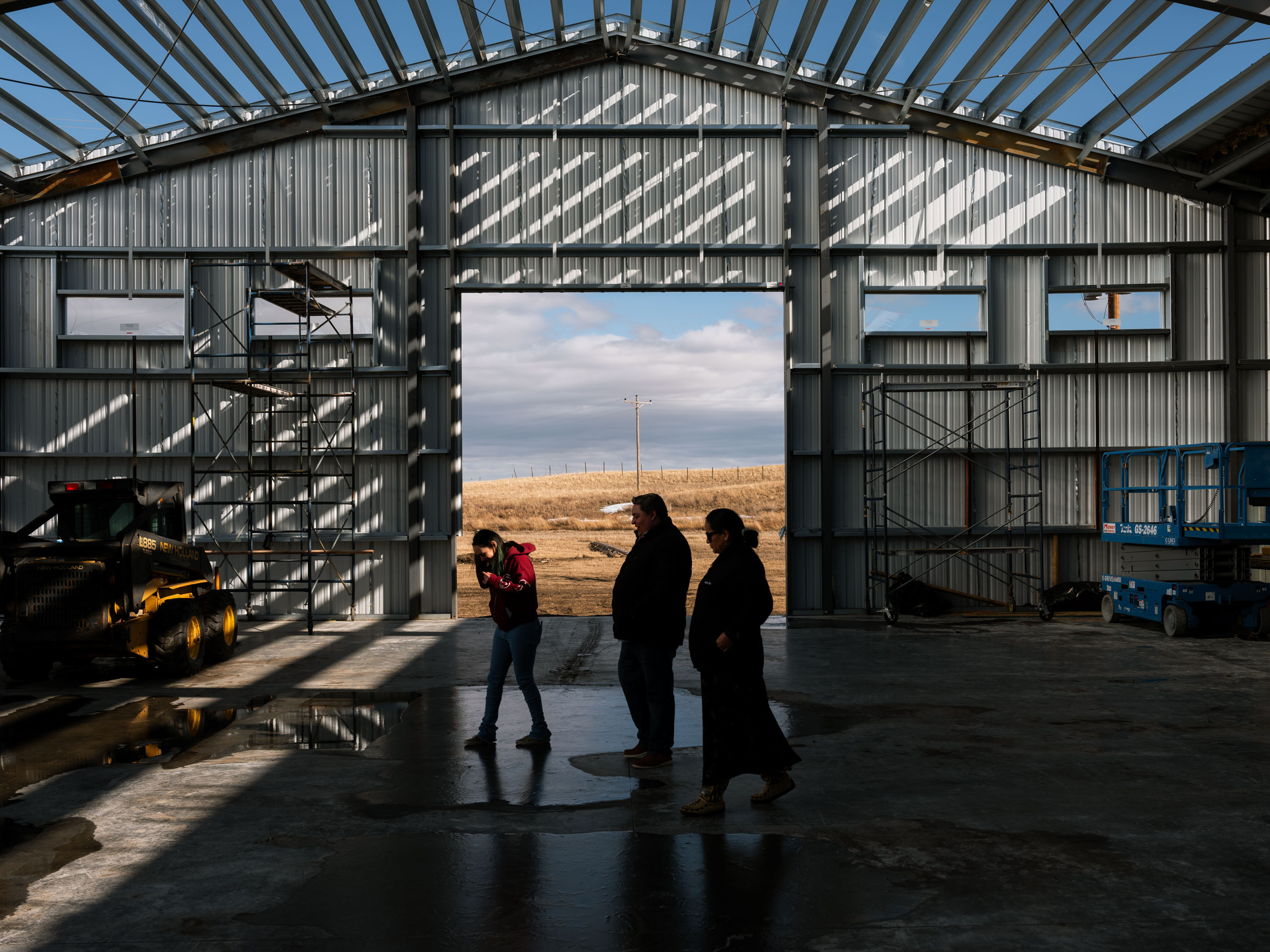 Three people in silhouette in the door of a half-finished building