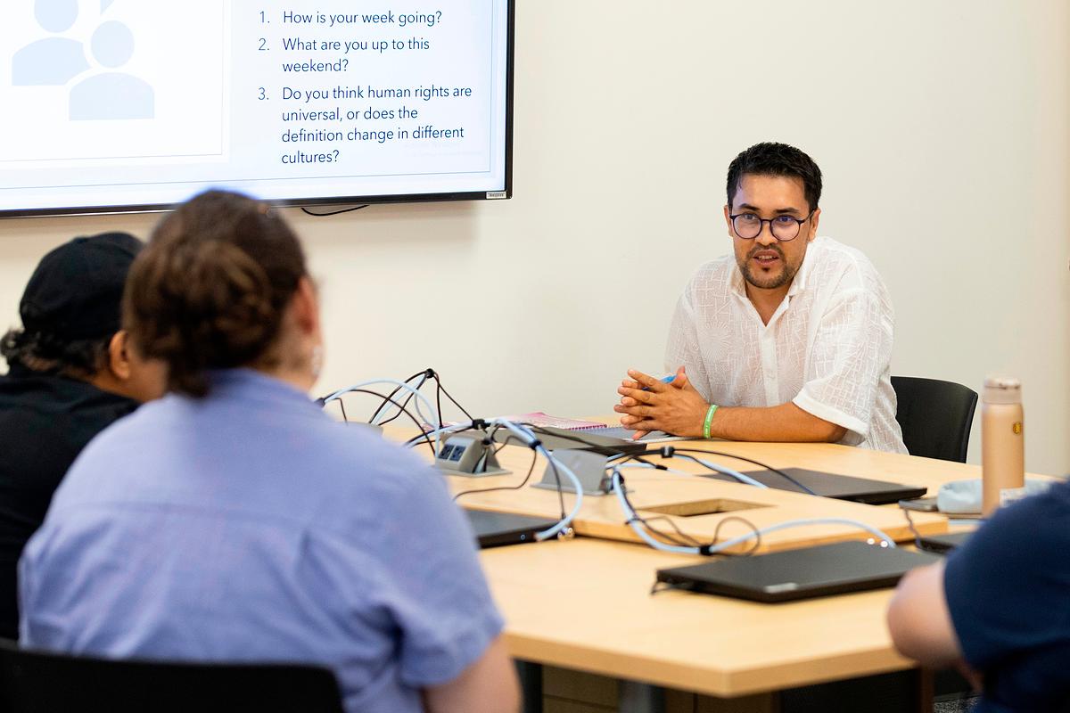Man at desk talks to others
