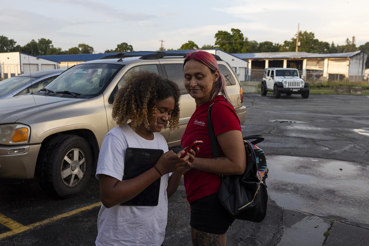 Woman and girl smile in parking lot.
