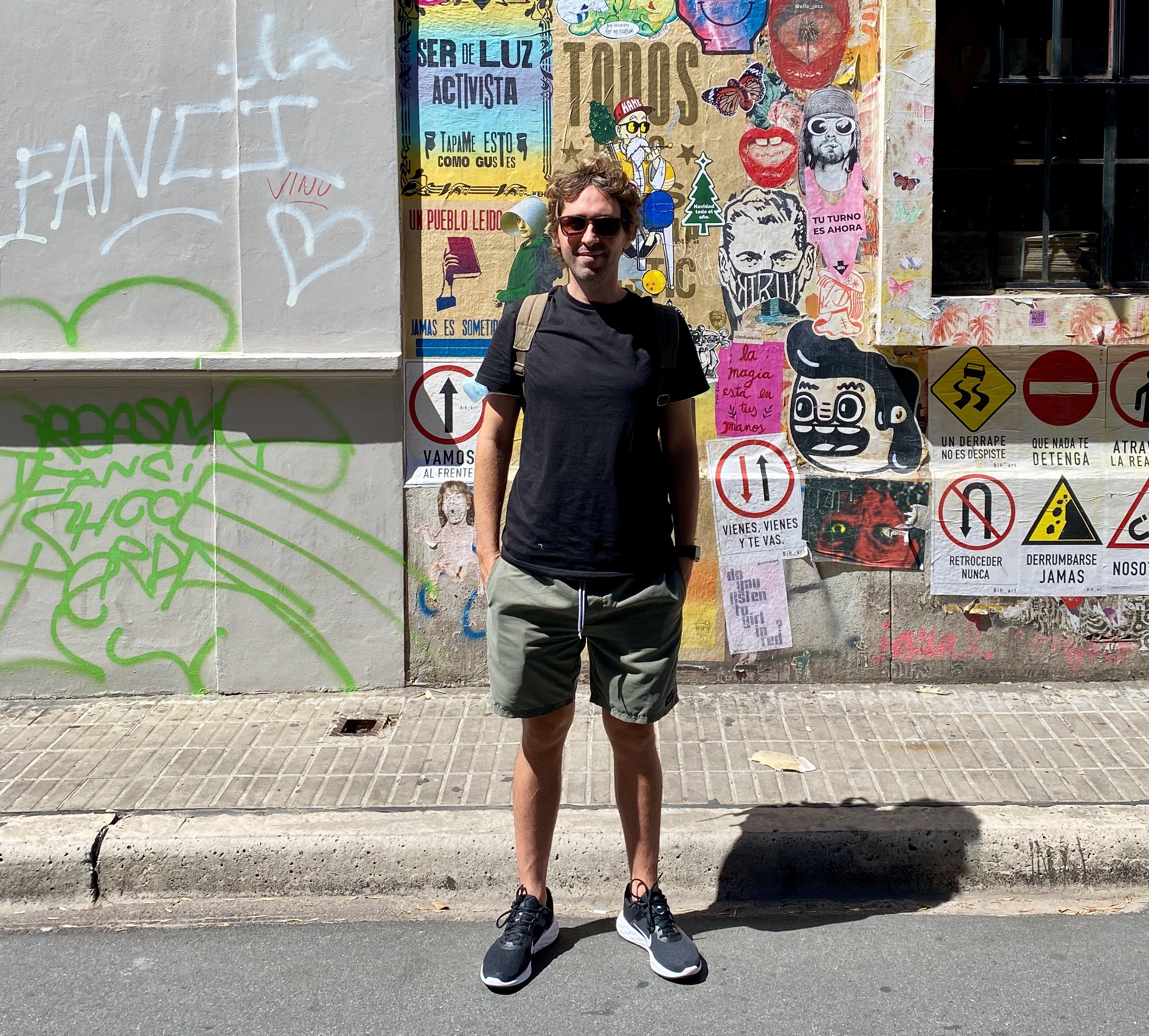 Juan standing in a astreet with murals behind him