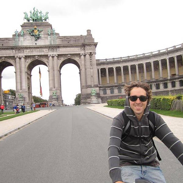 Juan riding a bicycle in a historical city during his travels