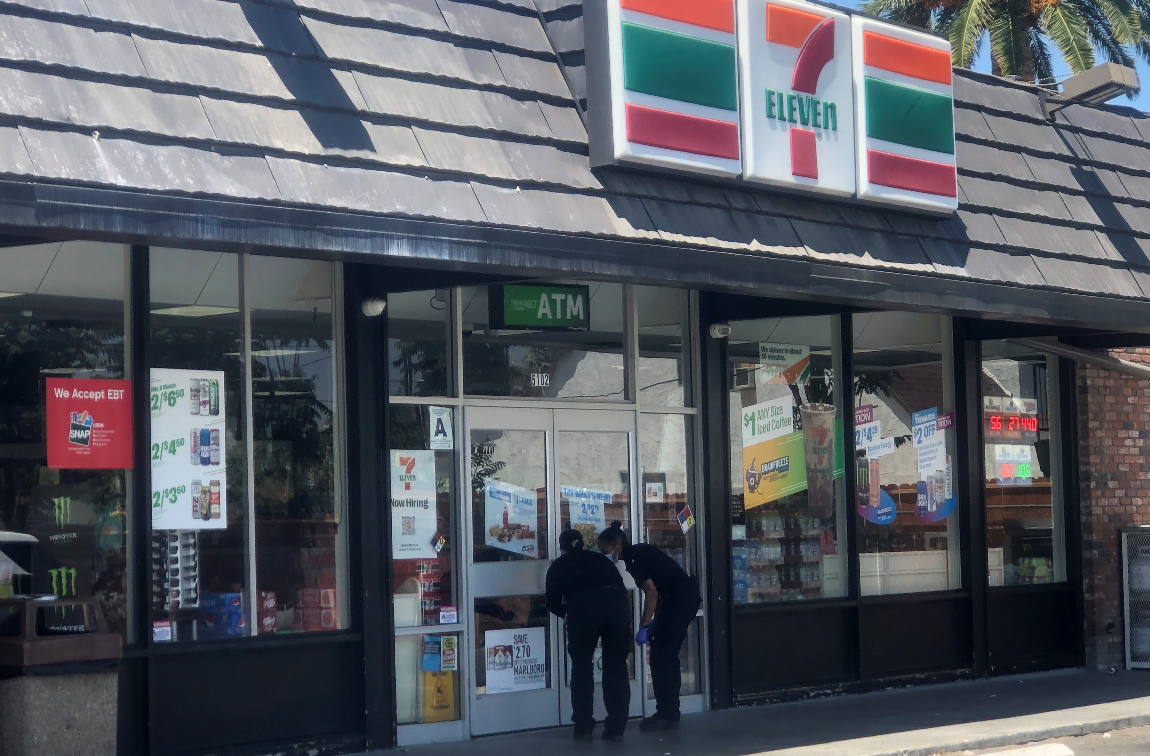 Riverside police evidence technicians examine the front door of the 7-Eleven on La Sierra Avenue where on July 11, 2022, a man robbed the store and shot a customer. (Brian Rokos, The Press-Enterprise/SCNG)