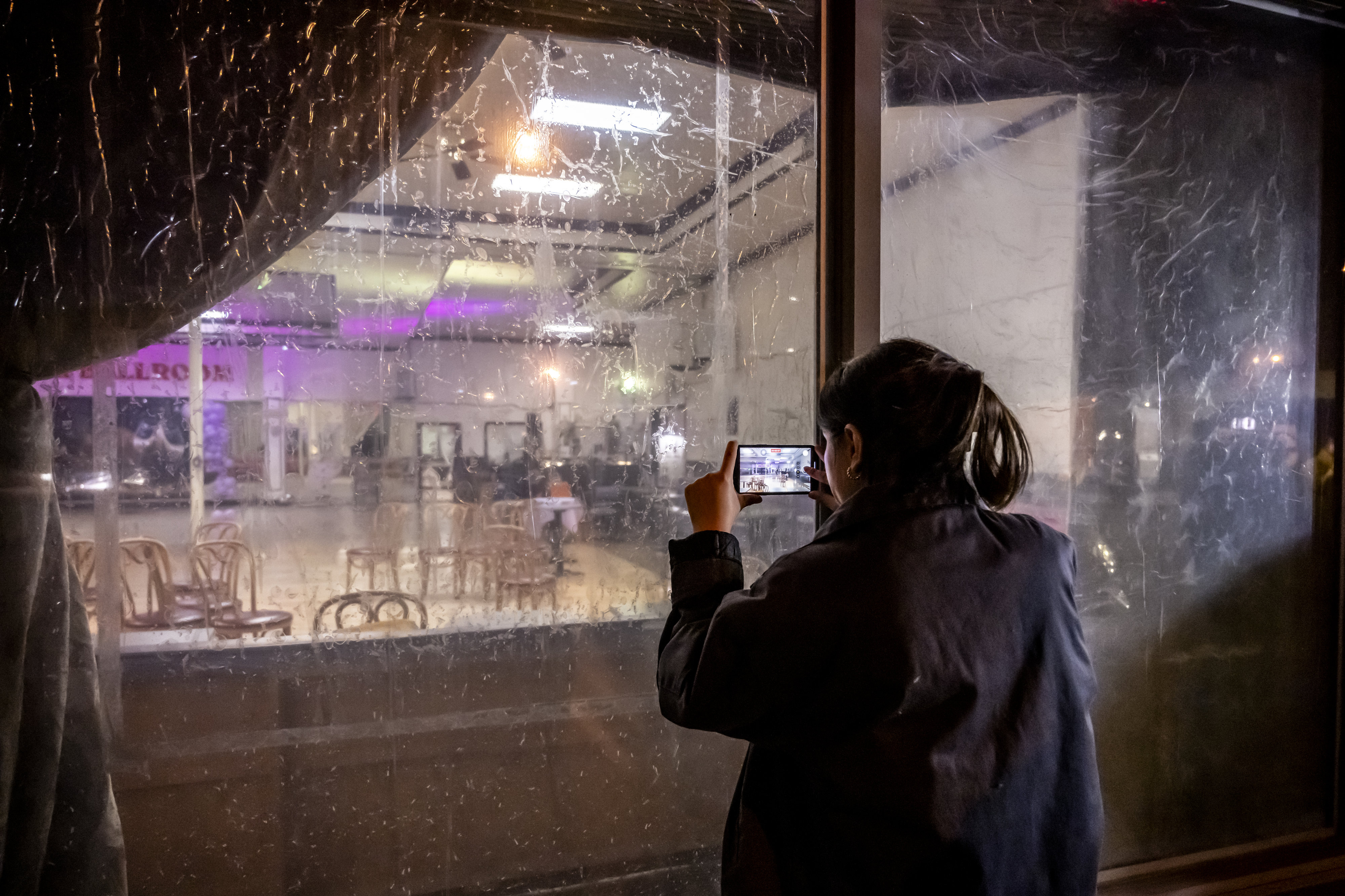 A woman takes cell phone photos through the front window of the Star Ballroom Dance Studio in Monterey Park on Sunday, January 22, 2023 after the police took down the crime scene tape following the deadly shooting of 10 people at a ballroom late Saturday night.