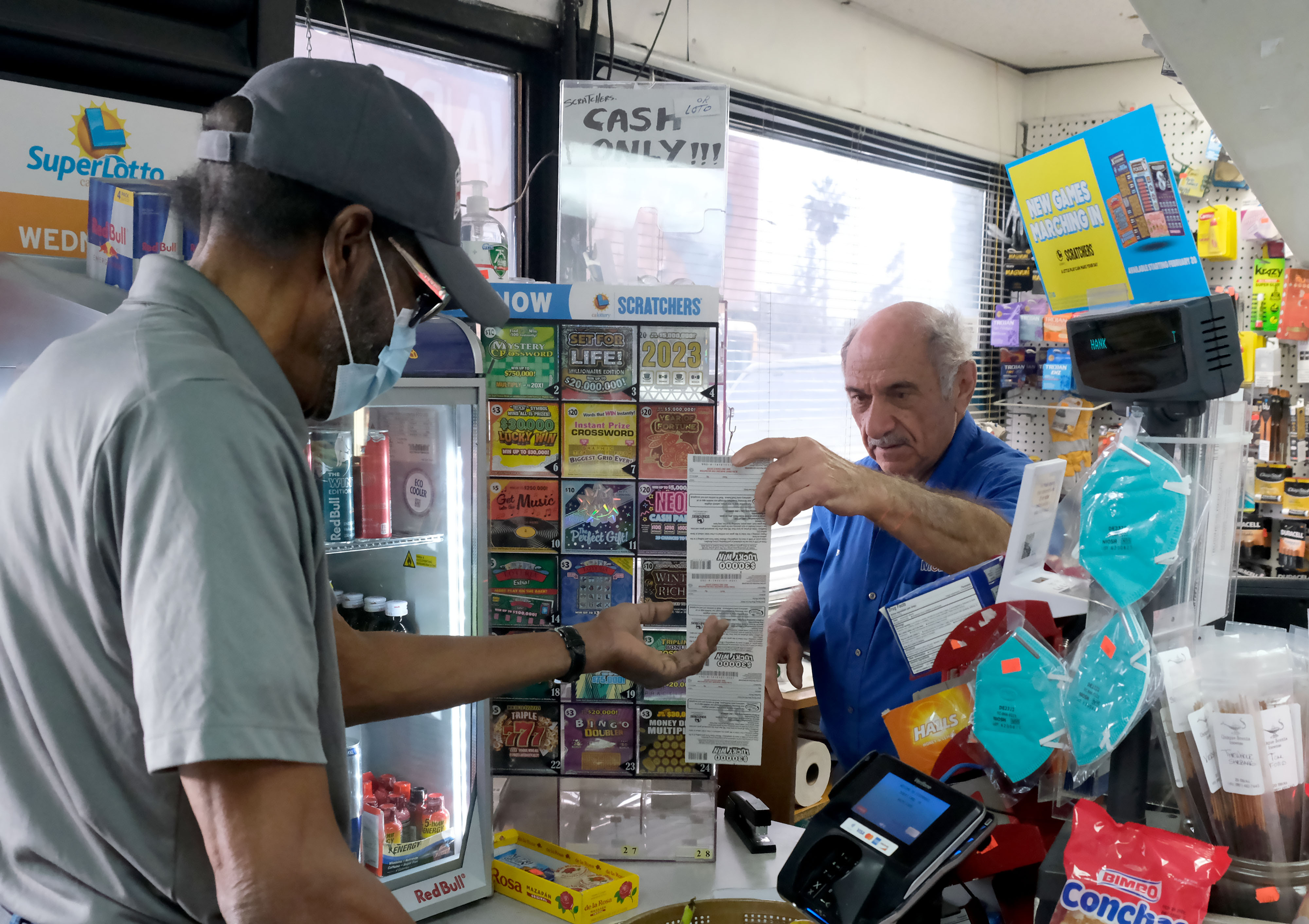 A customer purchases lottery scratcher tickets from Joe Chahayed at Joe's Service Center in Altadena on Tuesday, Feb. 14, 2023.