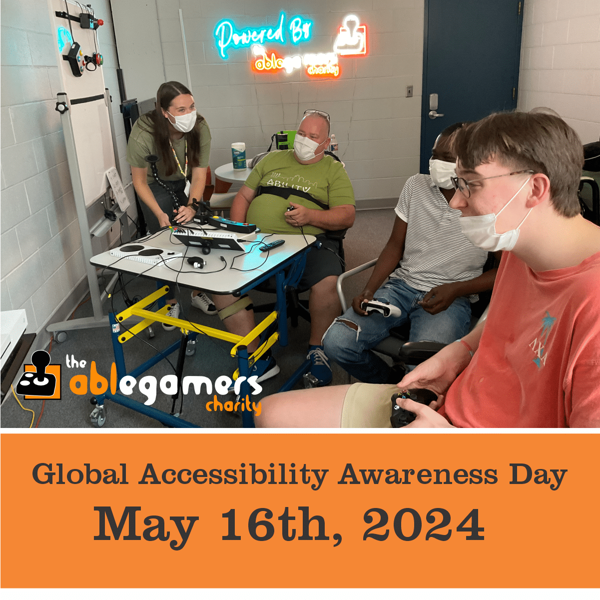 Three individuals playing a video game together and another indivdual standing in the background at Powered by AbleGamers partner Ability KC- Global Accessibility Awareness Day May 16, 2024