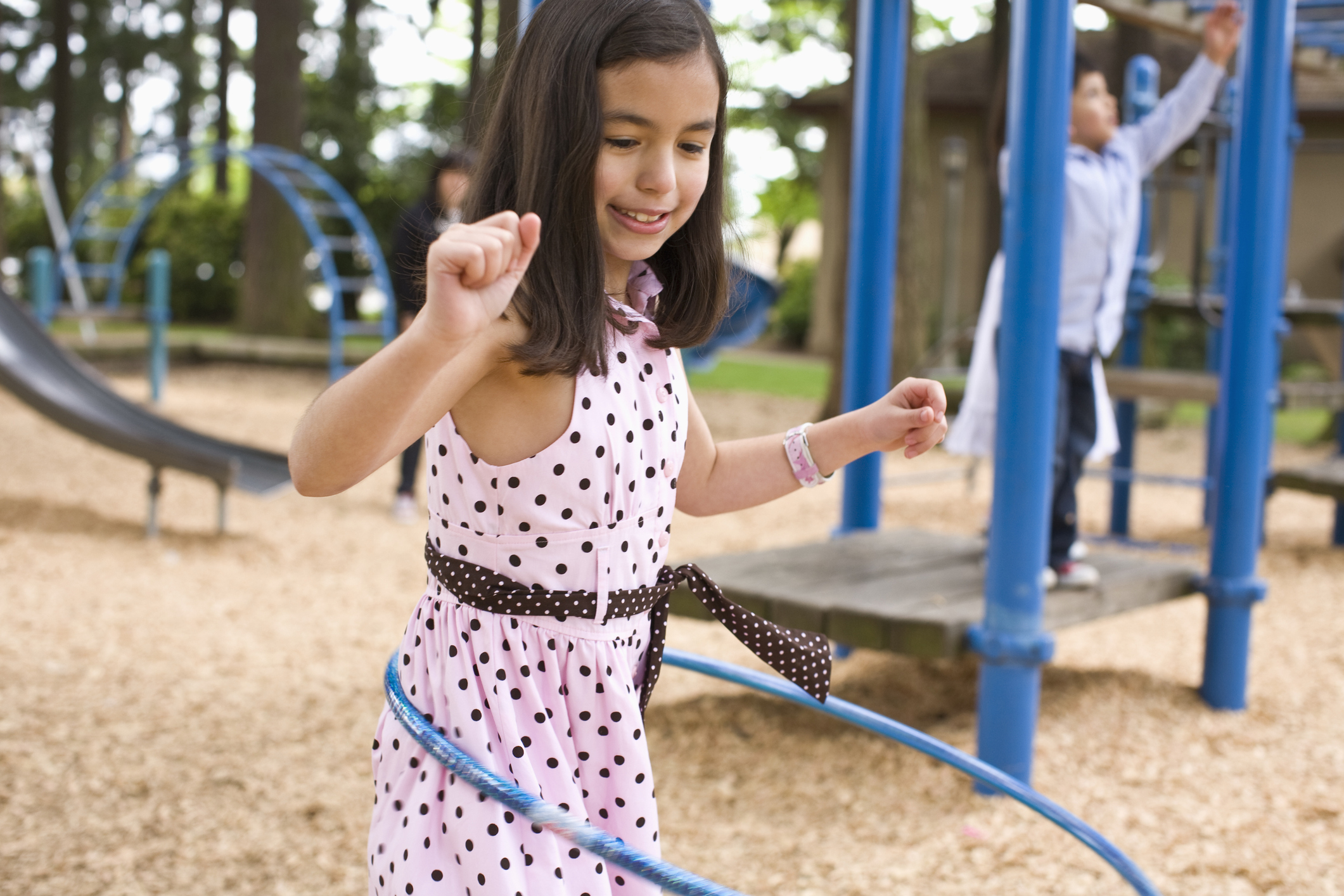 A girl is hula-hooping on the playground, but ostracized for being hyperactive.