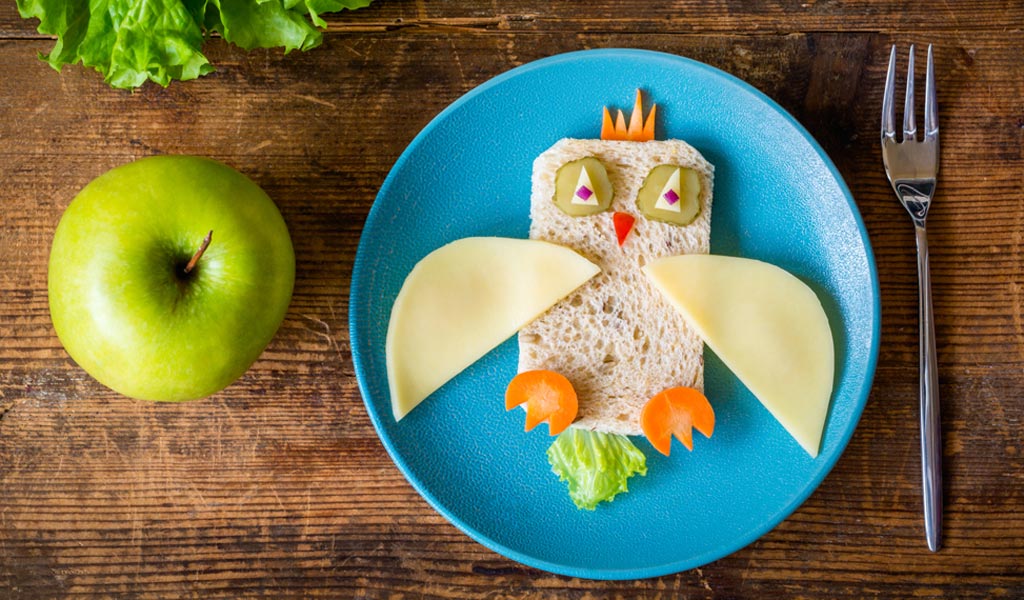 Bread, cheese, carrots, pickles arranged to look like a bird with an apple next to it makes for a healthy snack for kids with ADHD