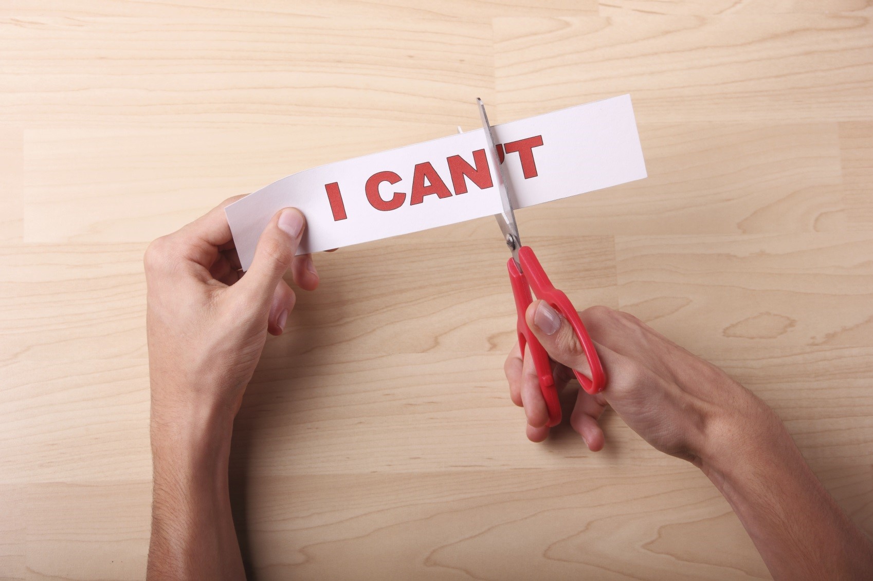 Scissors cutting the "t" off "I can't" to turn negative self talk into positive
