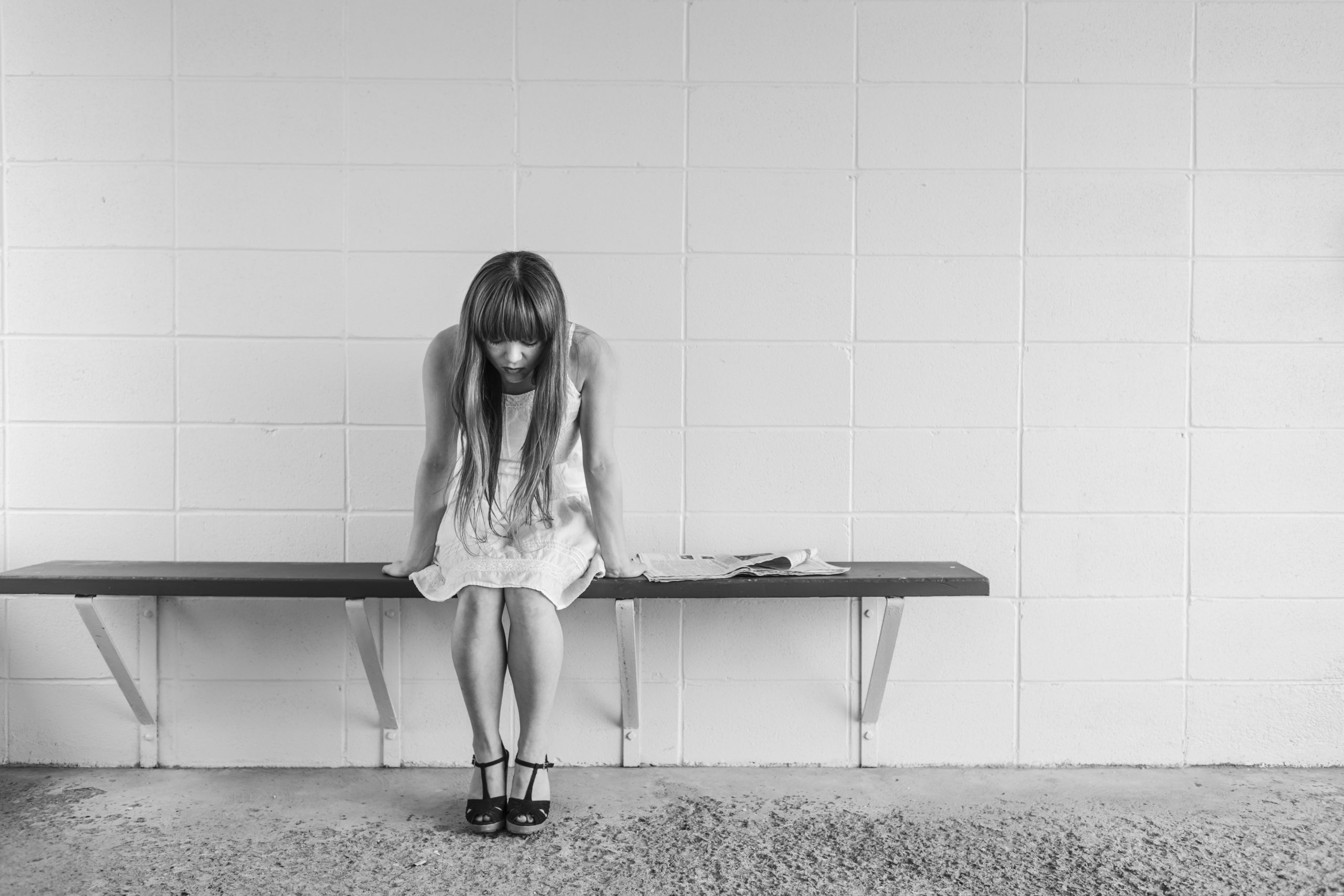 Woman showing signs of autism in adults sits alone on a bench feeling emotional because she worries "I think I have ADHD."