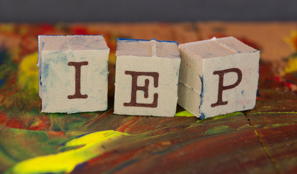 Three blocks spelling "IEP" on paint covered table, which is important to know about if a child has ADHD