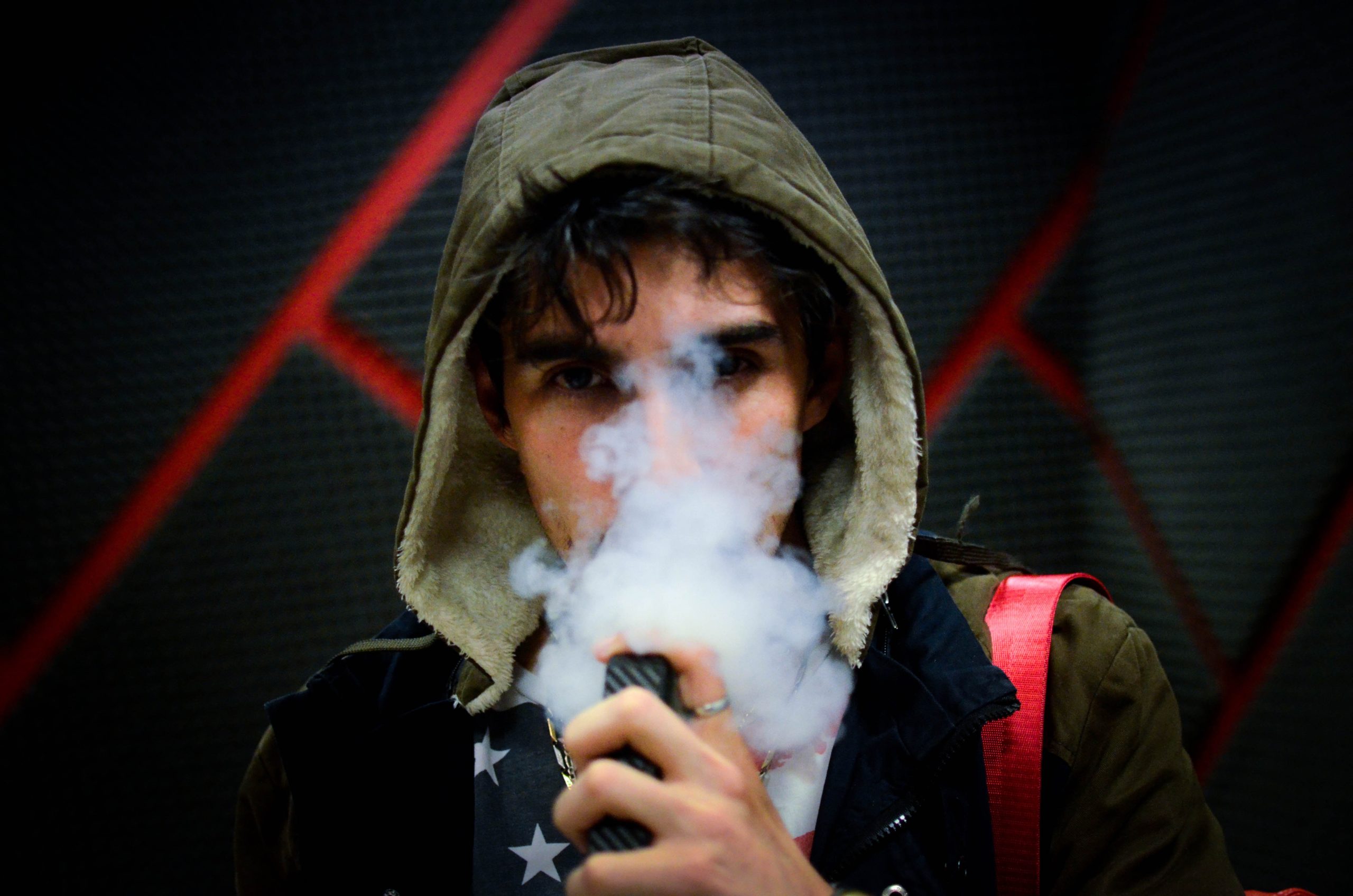 teenage boy vaping with face partially covered from smoke