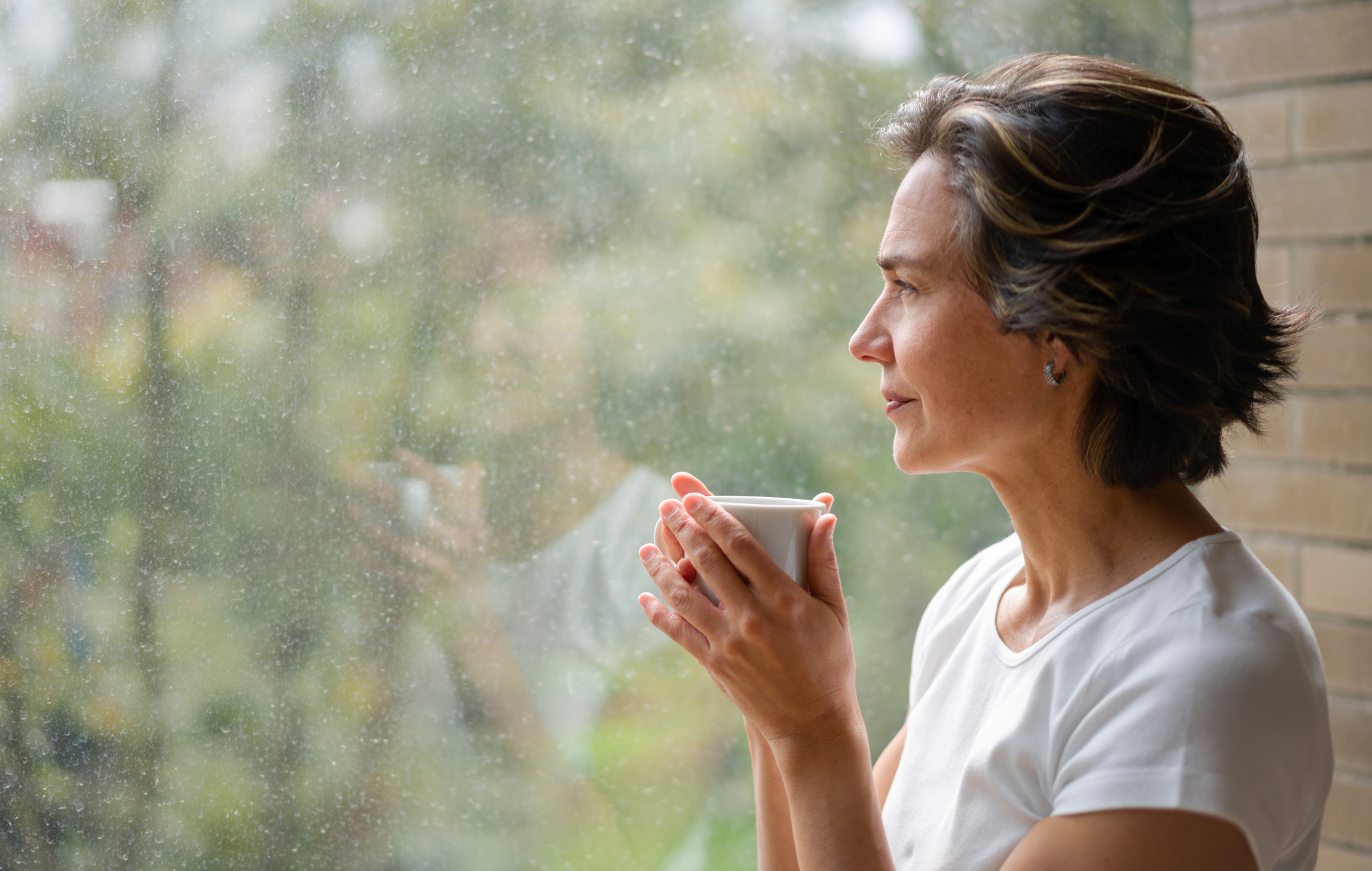 Thoughtful senior woman looking out the window wondering whether she should pursue an ADHD diagnosis as an older adult after age 50