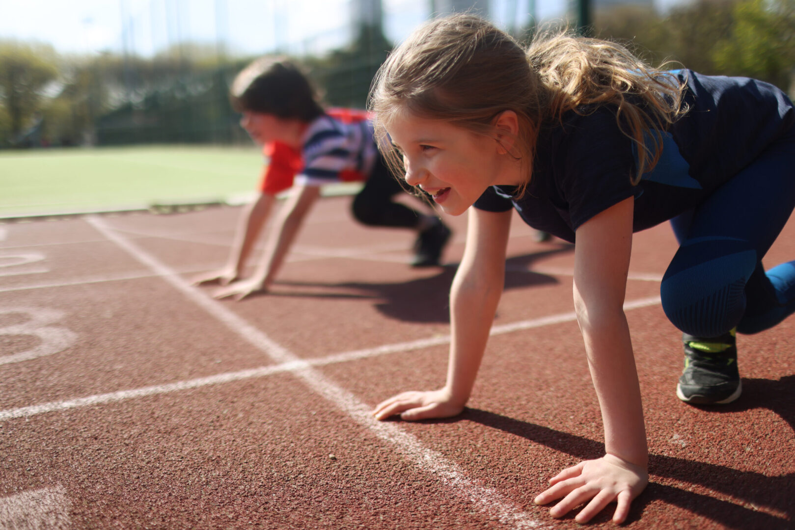 Young girl and boy ready to race on an athletics track