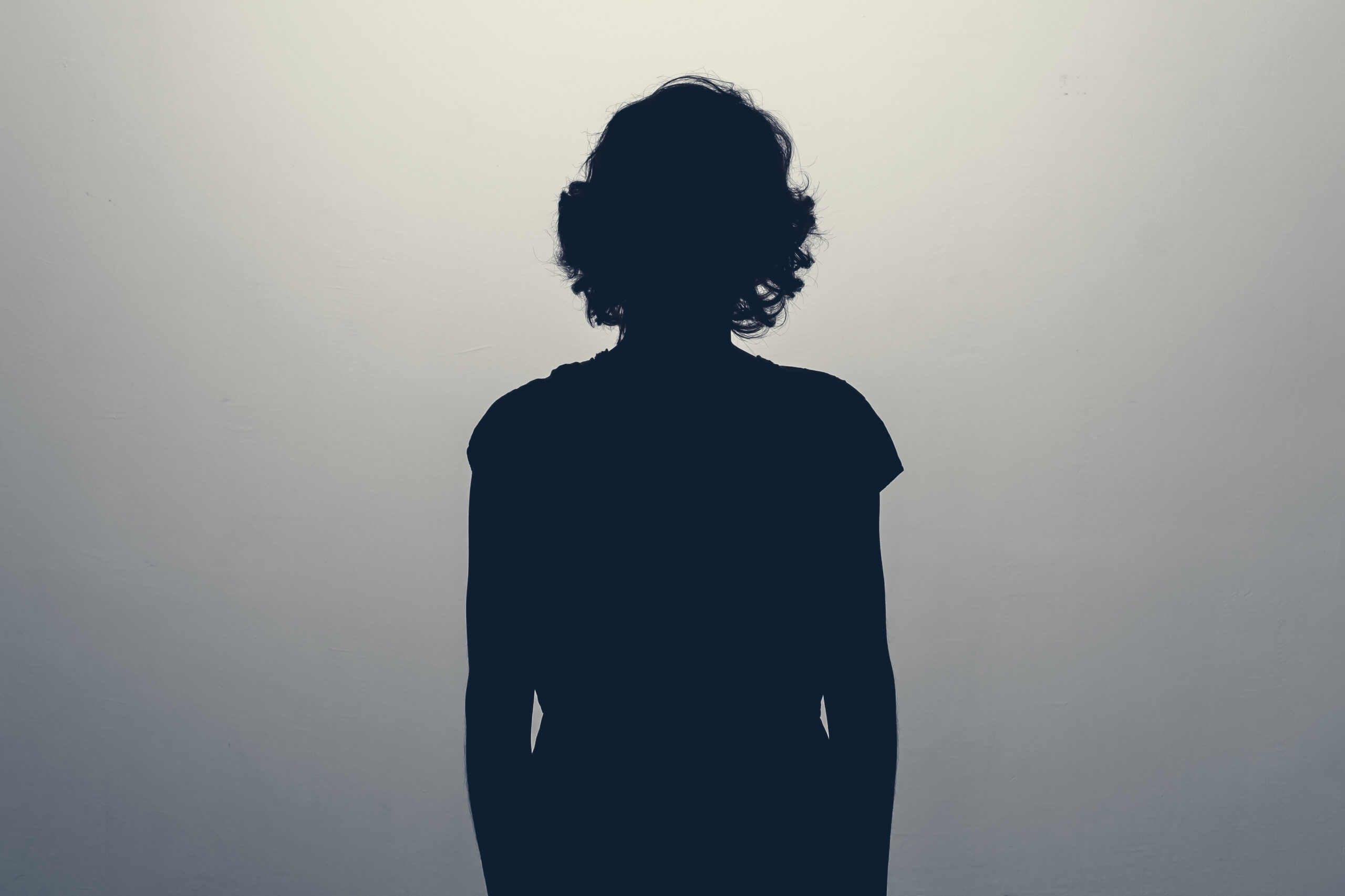 Female silhouette with short, curly hair against a faded grey background.