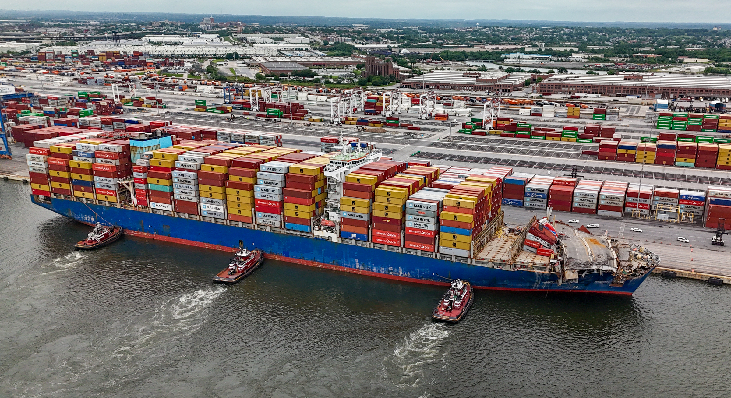 Tugs hold the container ship Dali against the pier at the Seagirt Marine Terminal after it was freed from the wreckage of the Francis Scott Key Bridge. There are far fewer containers stacked at the port because of the impact to the shipping channel. (Jerry Jackson/Staff)