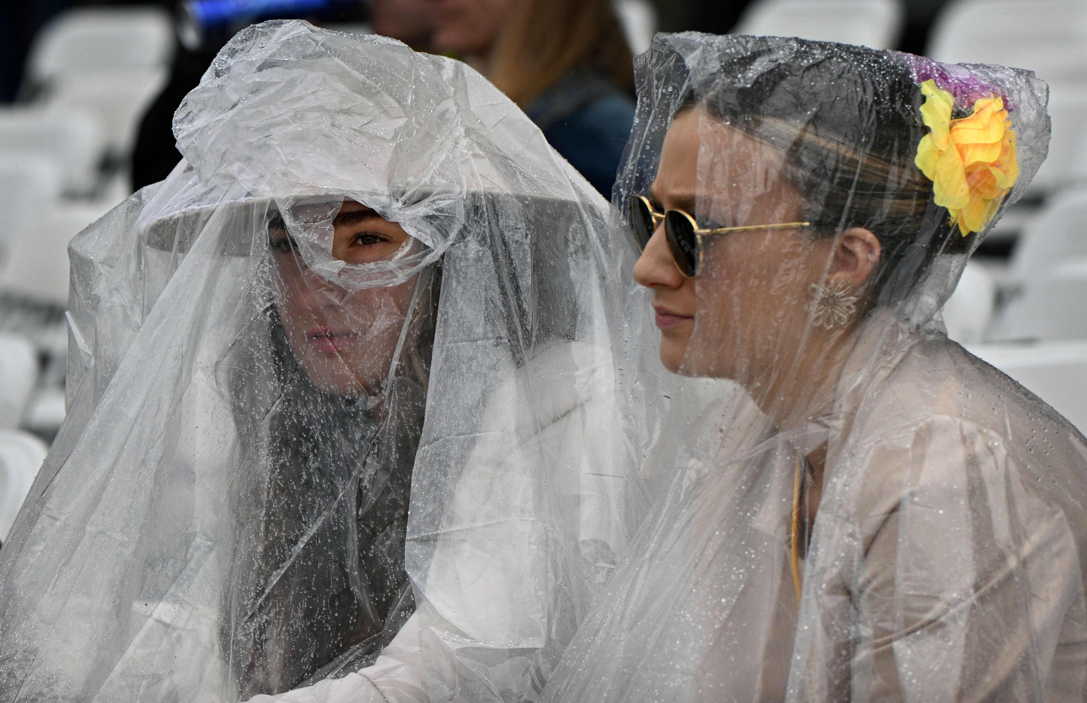 Rosina Aiello, left, of Long Island, and sister Gianna, wear ponchos over their Preakness outfits for their first Preakness Stakes at Pimlico Race Course. (Kenneth K. Lam/Staff)