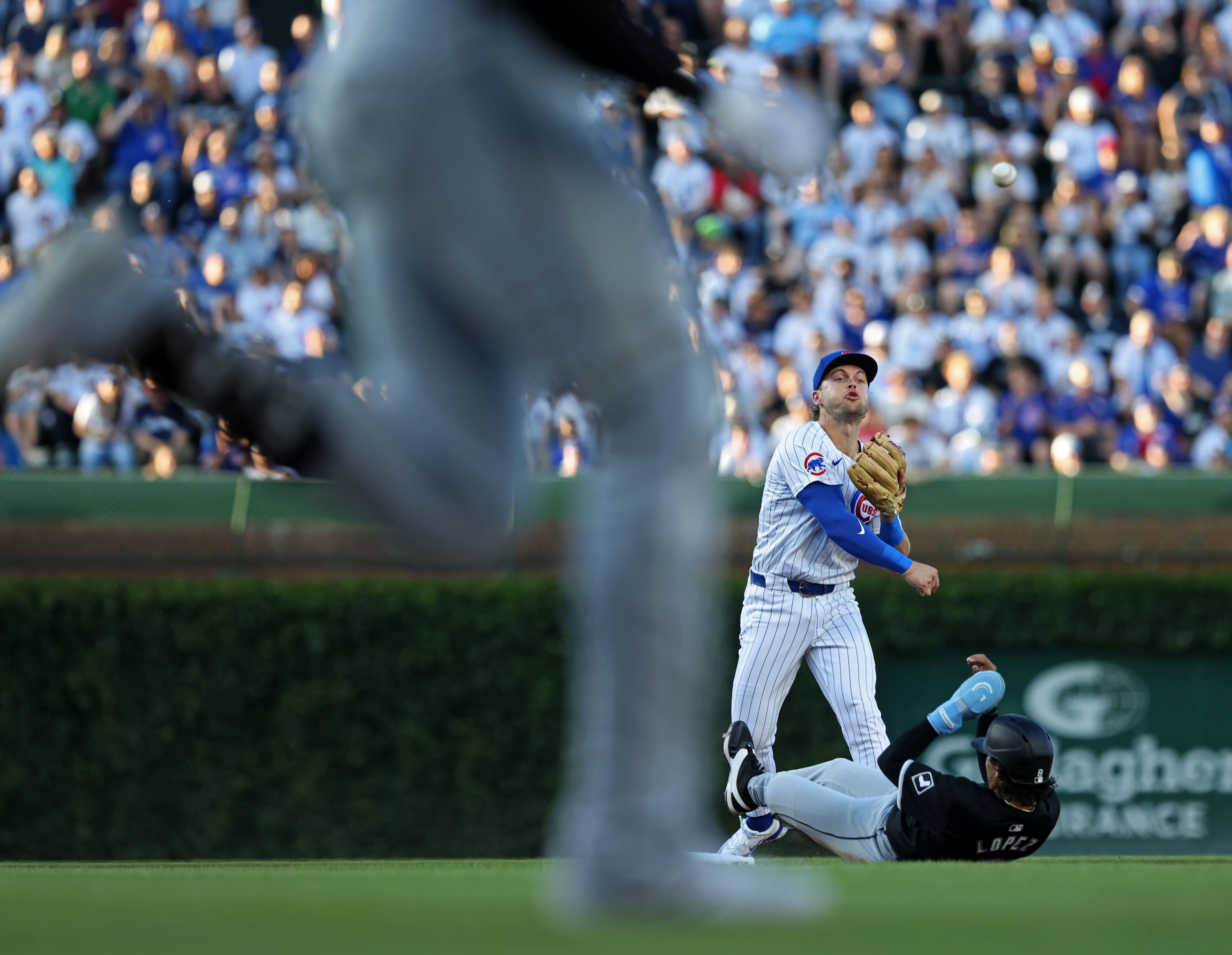 Cubs second baseman Nico Hoerner (2) throws to first base to complete a double play against White Sox second baseman Nicky Lopez (8), bottom, and centerfielder Luis Robert Jr., left, in the first inning at Wrigley Field on June 5, 2024, in Chicago. (John J. Kim/Chicago Tribune)