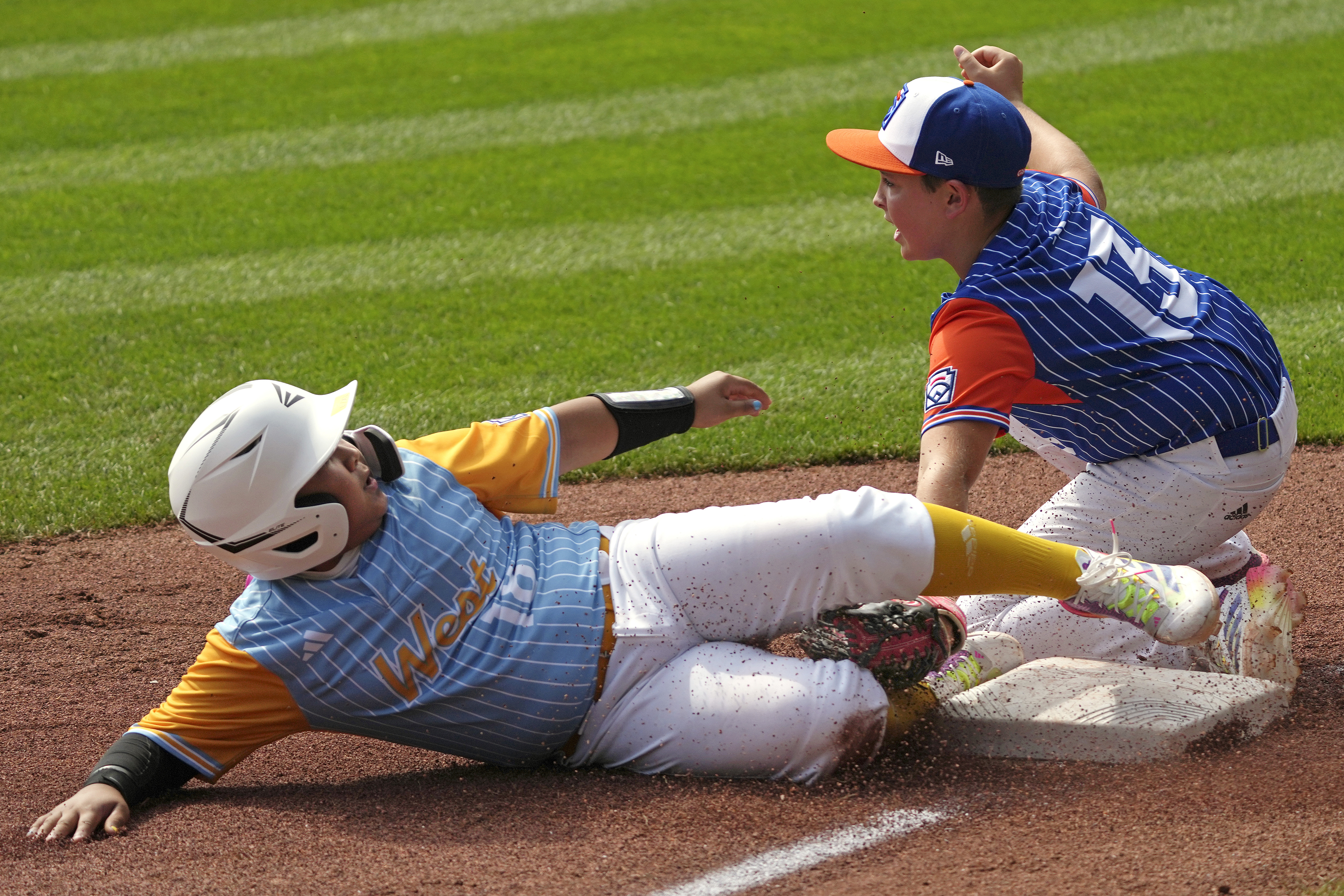 Hinsdale, Ill.'s Alex Vivanco (13) tags out Wailuku, Hawaii's Brextyn Kamaha'o Hong (18) at third base during the first inning of a baseball game at the Little League World Series in South Williamsport, Pa., Friday, Aug. 16, 2024. (AP Photo/Gene J. Puskar)