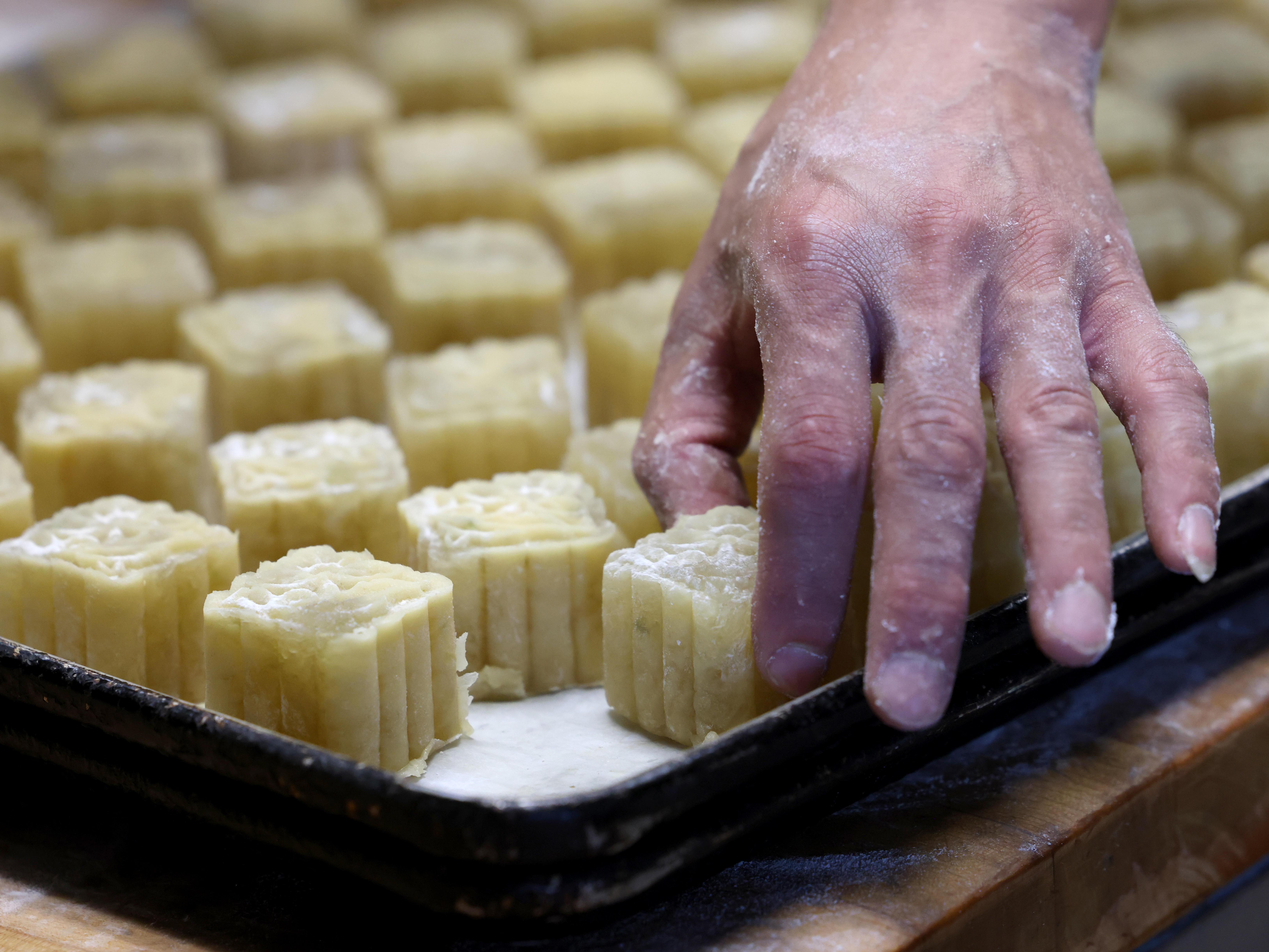 Bakers use plastic molds as they crate dozens of mooncakes at Chiu Quon Bakery in Chicago's Chinatown on Sept. 5, 2024. (Antonio Perez/Chicago Tribune)