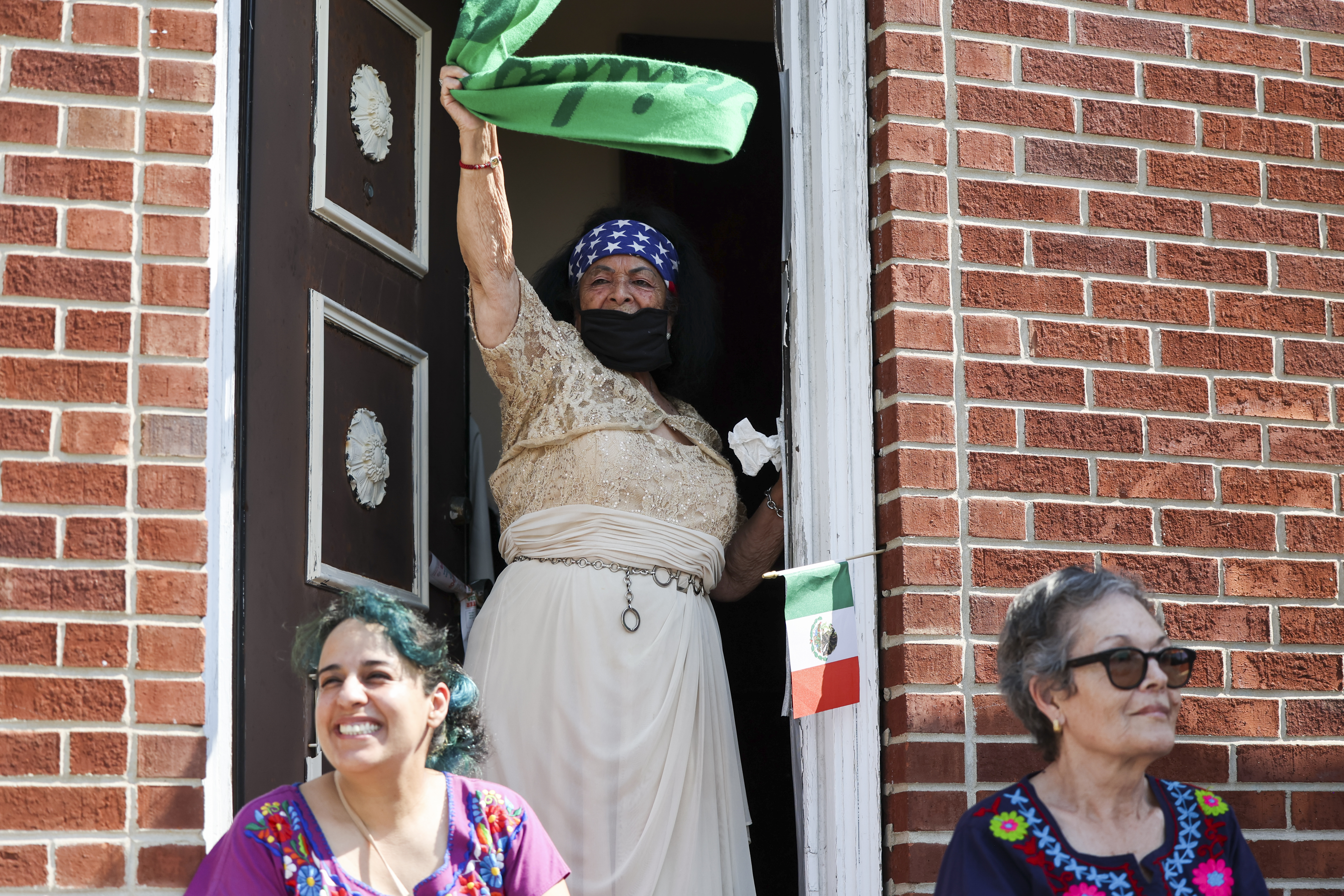 Manuela Aguilar, top, and Veronica Banda sit outside their building to watch the Mexican Independence Day Parade in Little Village on Sunday, Sept. 15, 2024. (Eileen T. Meslar/Chicago Tribune)